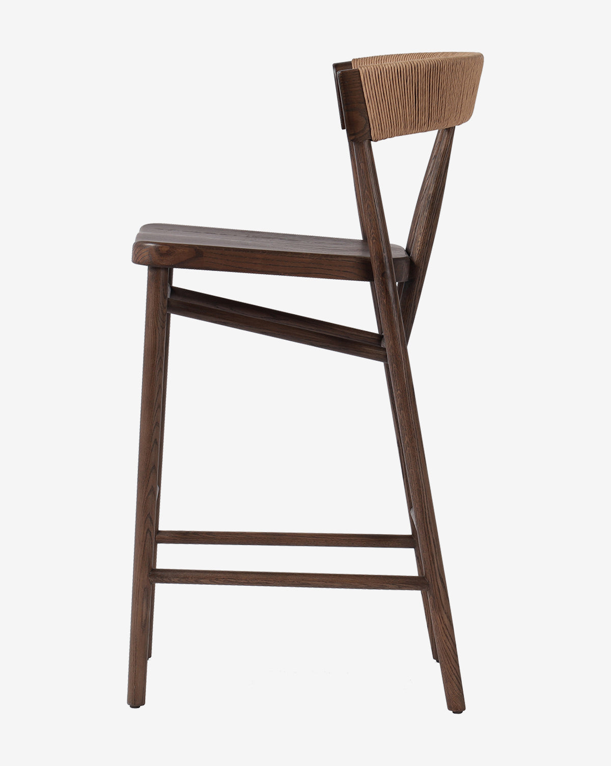 Side view of the Ardent Stool by Four Hands: a modern oak frame kitchen bar stool with a dark finish, flat seat, angled backrest with natural paper rush weave, and footrests connecting the legs. McGee & Co.