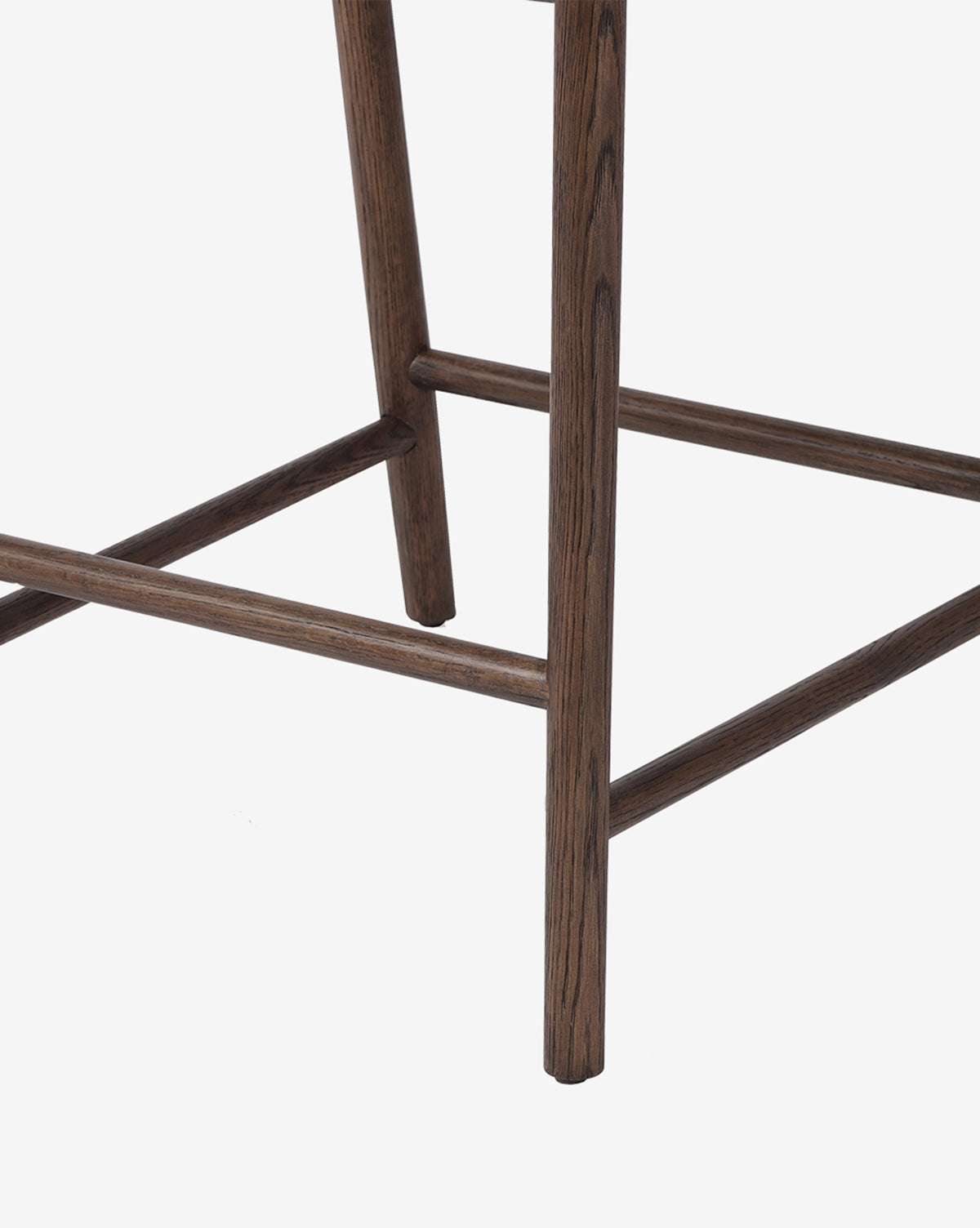 Close-up of the Ardent Stool by Four Hands, highlighting its oak frames wooden legs and crossbars with a dark wood finish and minimalist design, set against a plain white background. McGee & Co.