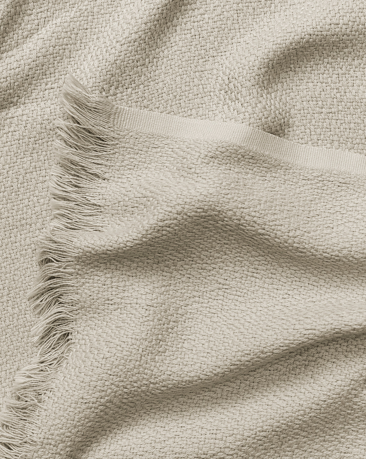 The Ariella Throw by J Call Designs LLC dba Sew Miami LLC features beige woven fabric with a textured pattern and fringed edge, appearing soft and cozy—the perfect neutral cotton blanket or stylish accent for your home. McGee & Co.