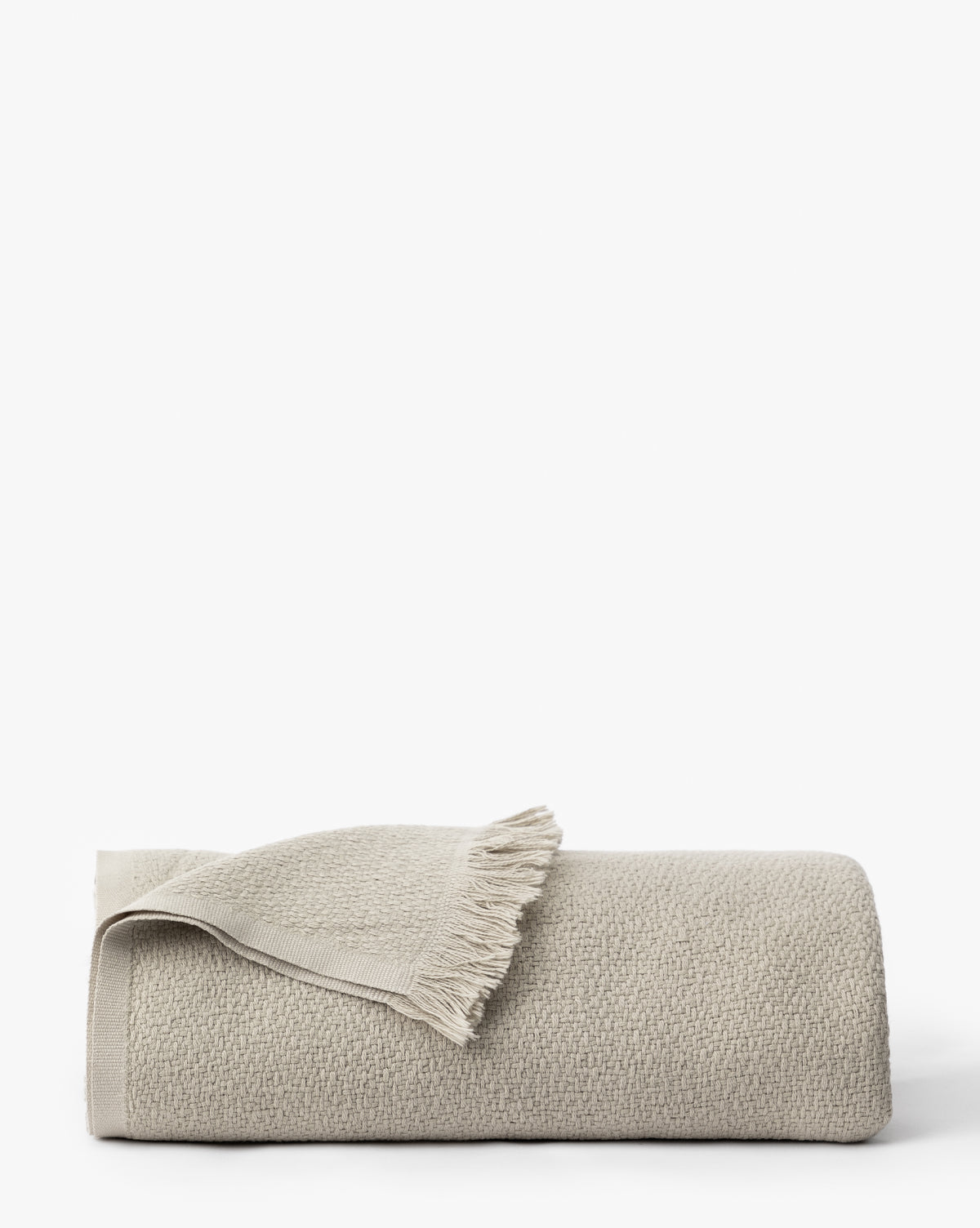 The Ariella Throw by J Call Designs LLC dba Sew Miami LLC is a folded, light beige cotton throw with a neutral palette and fringe on one end, displayed against a plain white background. McGee & Co.