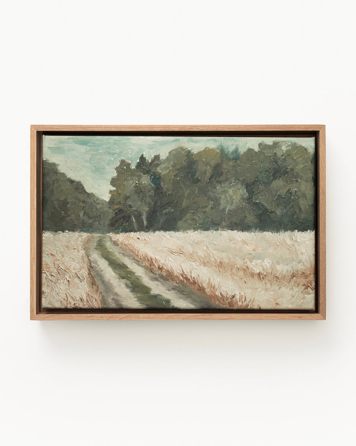 “Around the Bend” is a gallery-quality fine art print depicting a winding country path through tall grass and green trees beneath a cloudy sky—perfect as forest path wall art for any space, by McGee & Co.