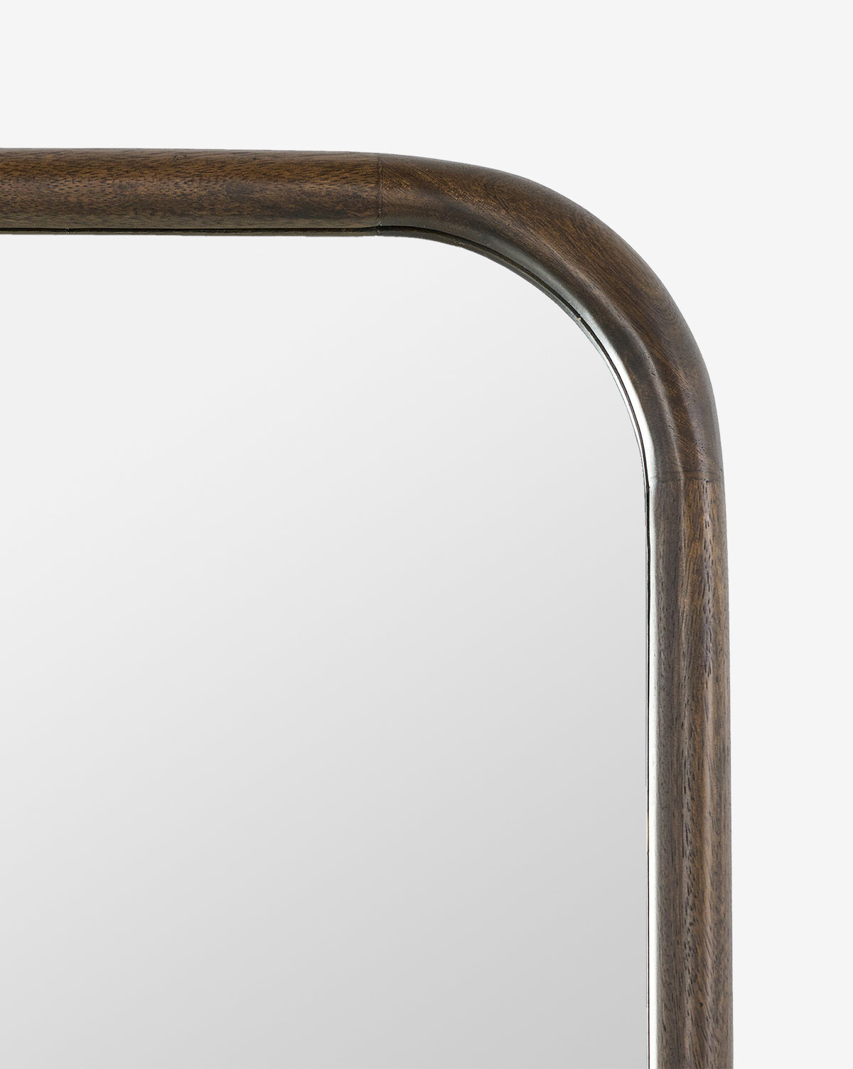 Close-up of the top right corner of the Arvid Wall Mirror, featuring a rounded solid mango frame in aged brown, highlighting smooth grain and joinery details against a plain white background, by McGee & Co.