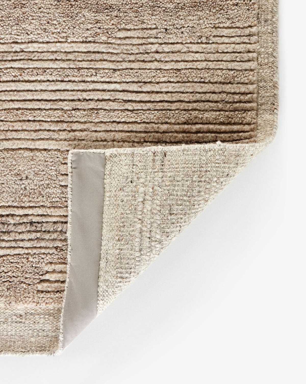 A corner is folded to show the woven underside and reinforced edge, emphasizing its quality craftsmanship and textured design, by McGee & Co.