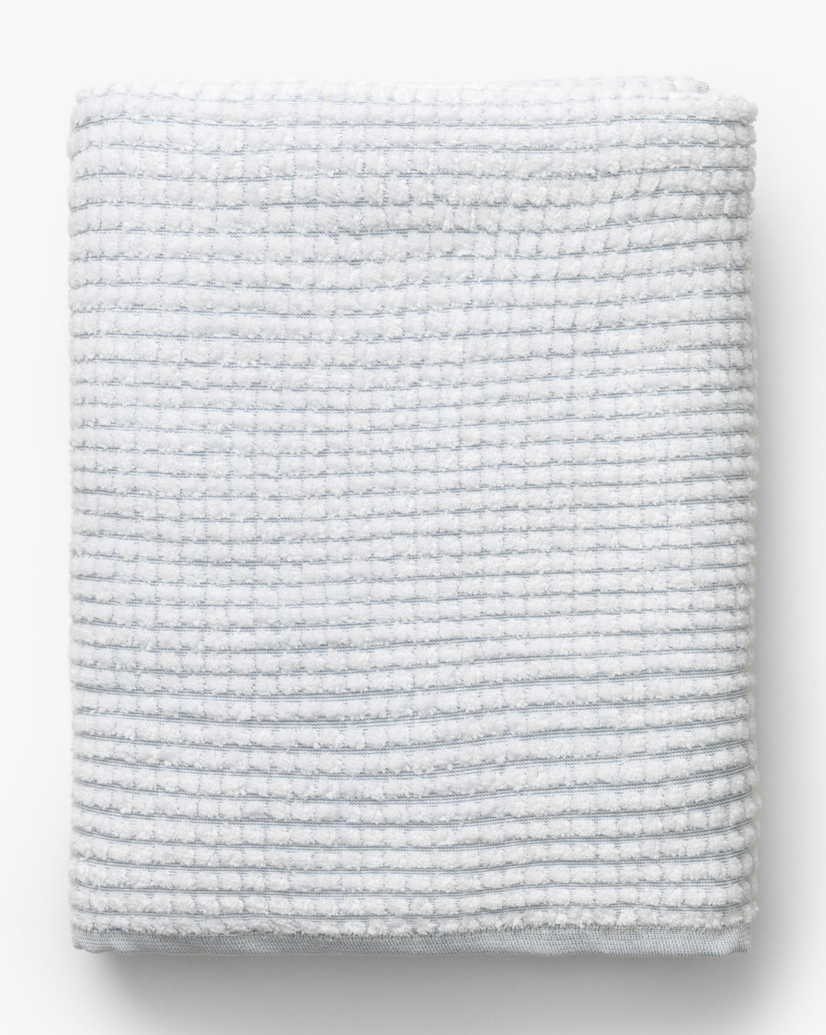 A neatly folded gray towel with a textured, grid-like pattern from our Atrani Gray Organic Bath Collection, displayed on a plain white background by McGee & Co.