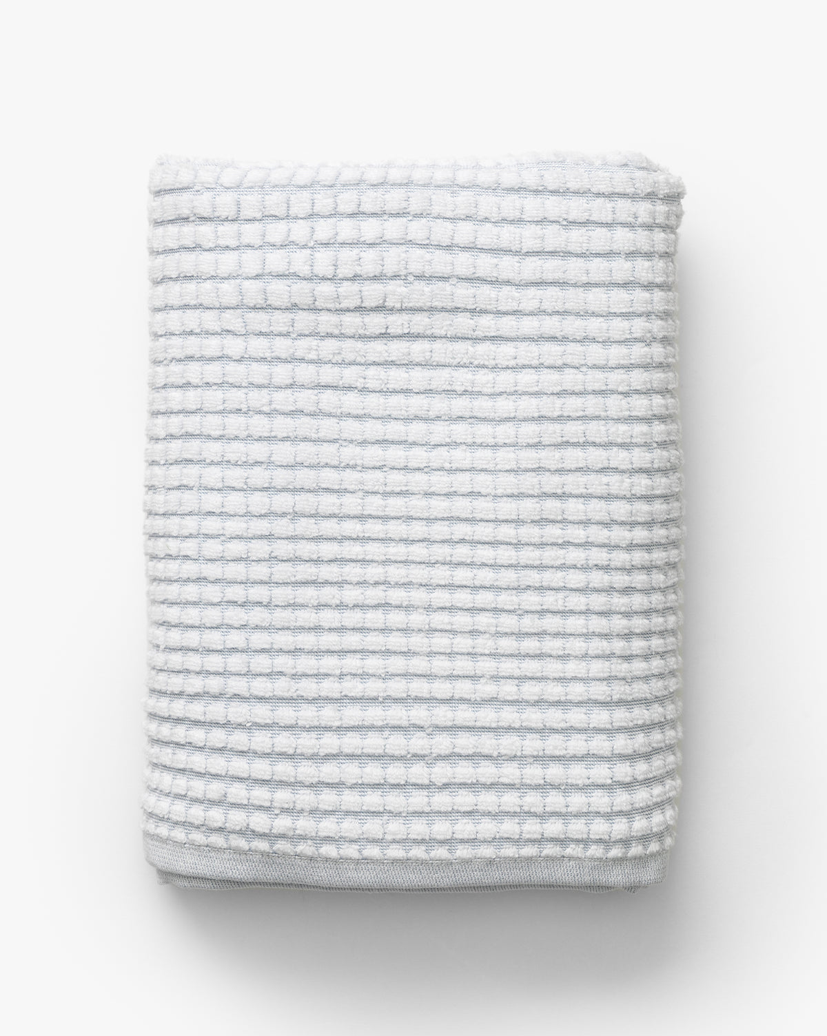 A neatly folded waffle weave towel in gray with a subtle grid pattern, placed on a plain background—an elegant addition to the Atrani Gray Organic Bath Collection, by McGee & Co.