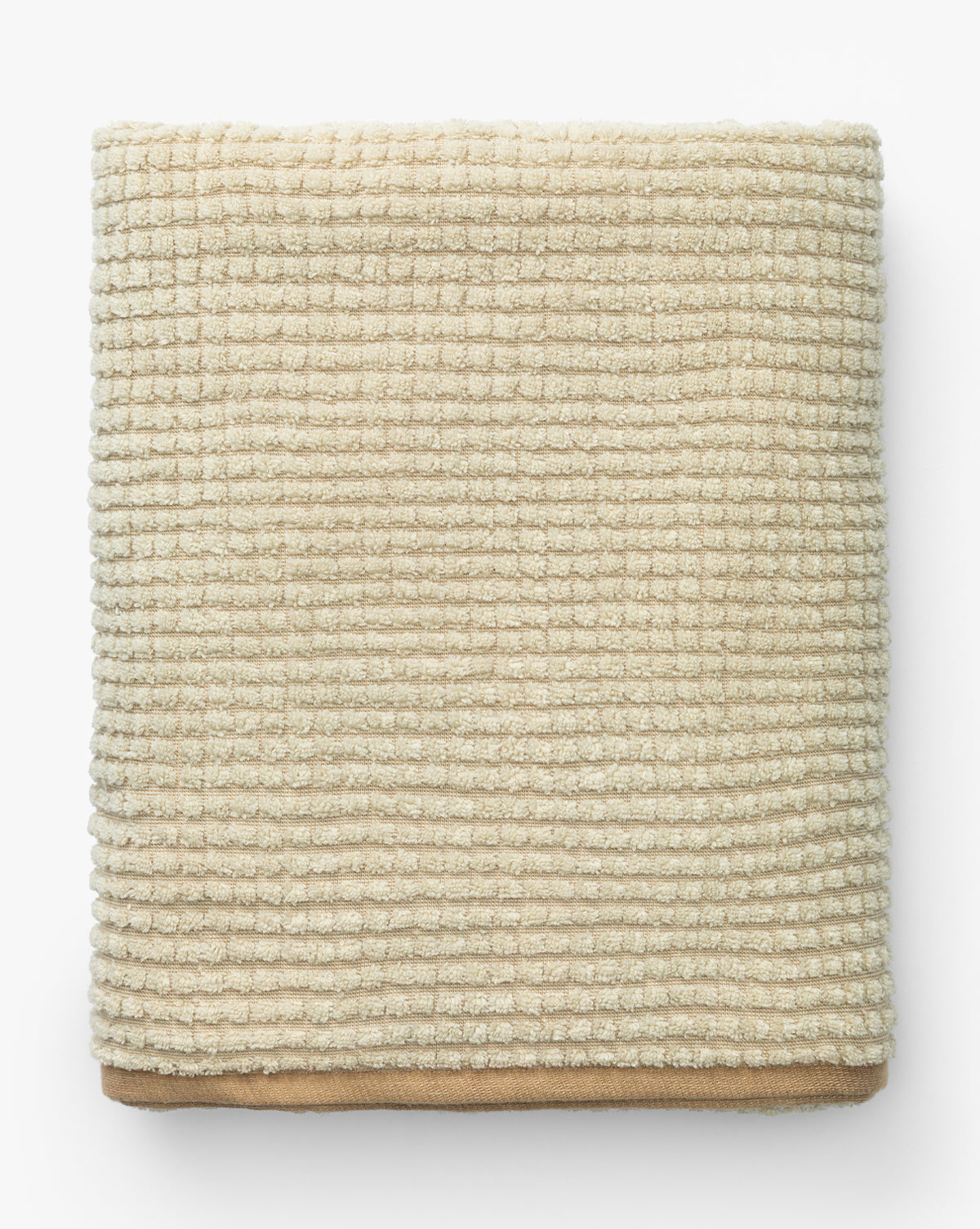 A neatly folded, beige, waffle weave towel from the Atrani Organic Bath Collection is placed on a white background by McGee & Co.