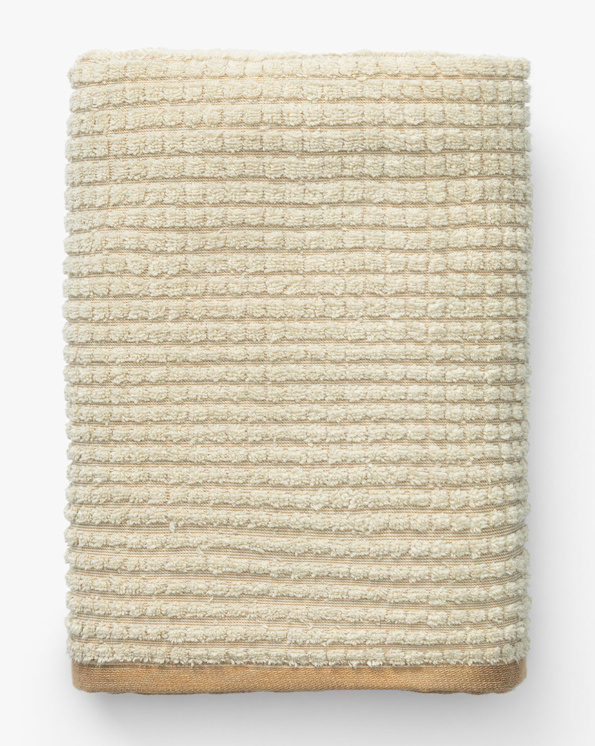 A neatly folded beige waffle weave towel from the Atrani Organic Bath Collection features a grid-like pattern and solid edge, shown from above on a white background, by McGee & Co.