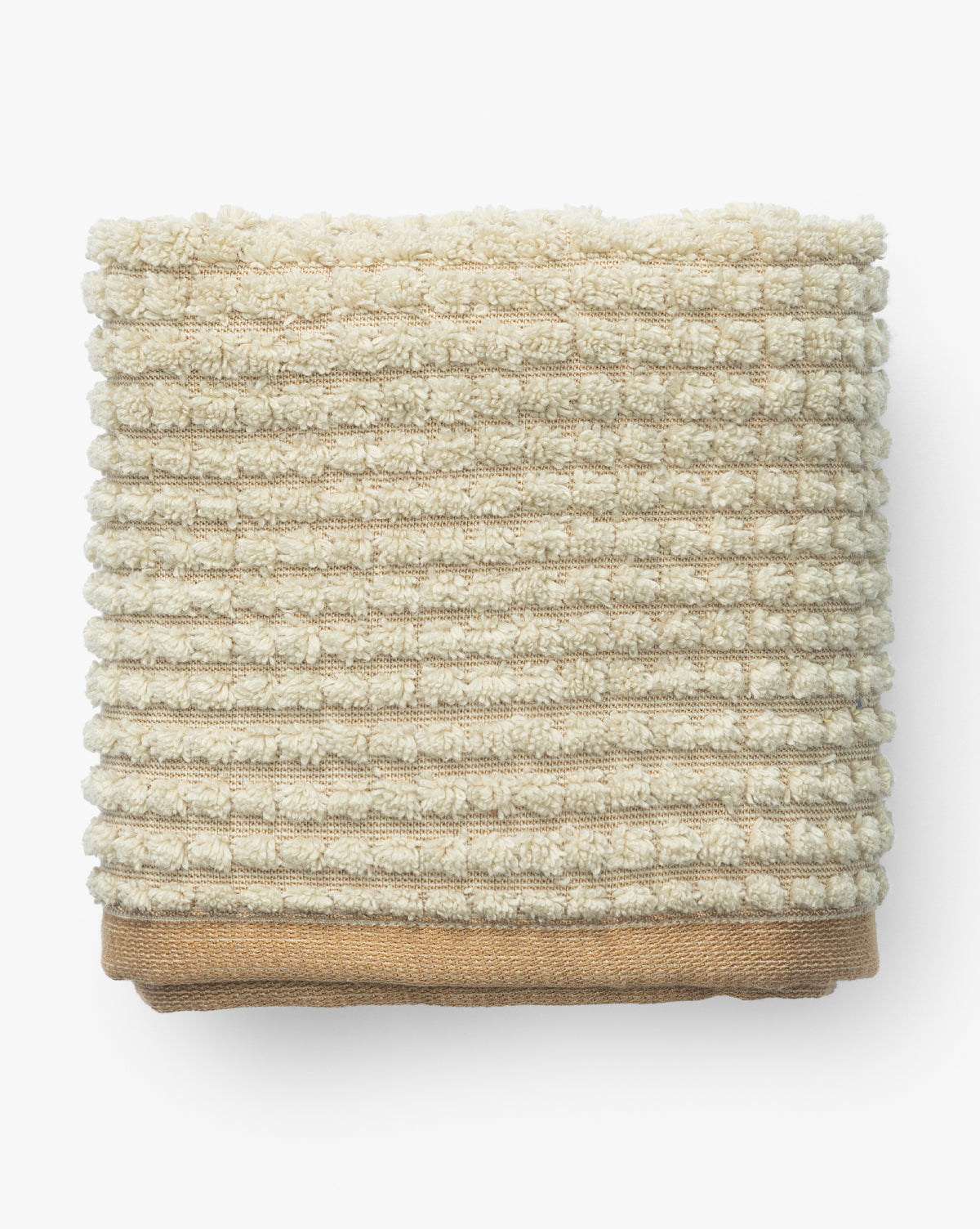 A neatly folded, ribbed beige towel from the Atrani Organic Bath Collection is stacked on a plain brown organic cotton towel, both set against a white background, by McGee & Co.