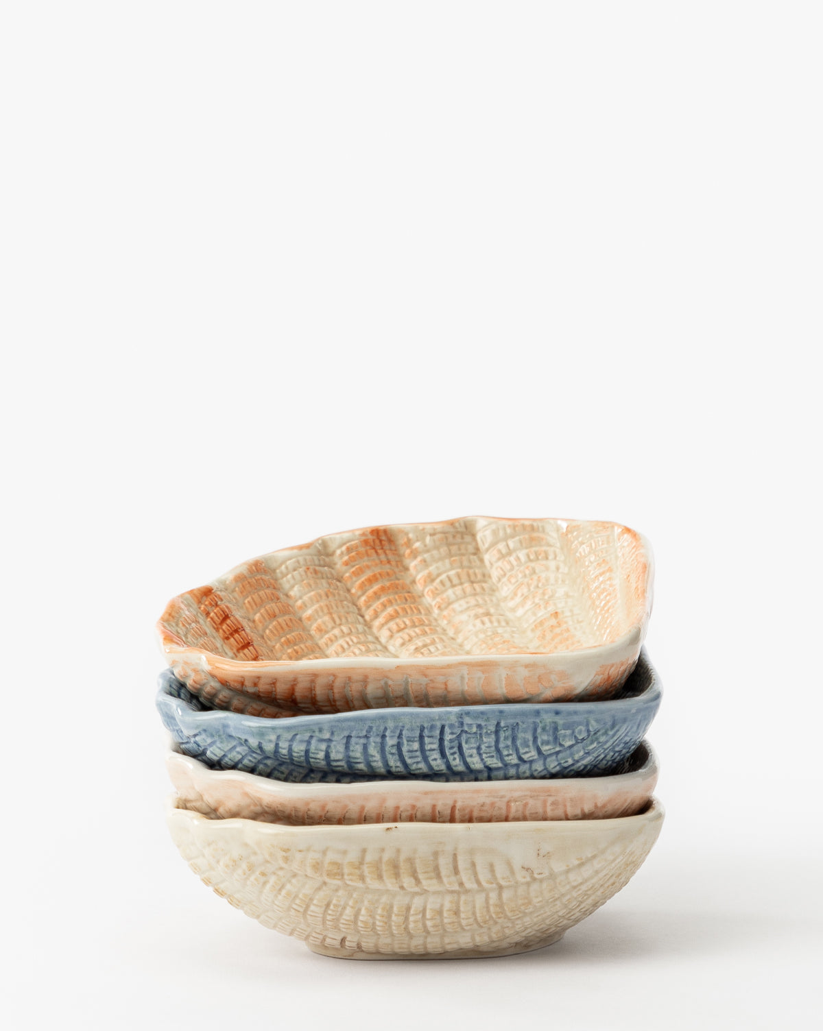 The Aurelie Shell Shaped Bowls (Set of 4) feature coastal-inspired, textured stoneware in cream, blue, and light orange tones. Each bowl has wavy edges and a shell shape, all set against a plain white background by McGee & Co.