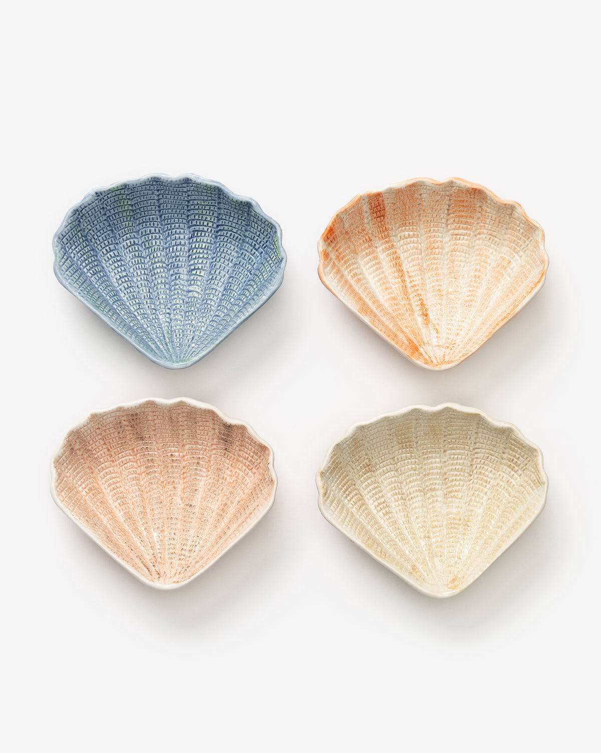 The Aurelie Shell Shaped Bowls (Set of 4) features pastel blue, orange, pink, and cream stoneware bowls arranged in a grid—ideal for bringing coastal charm to your table, by McGee & Co.