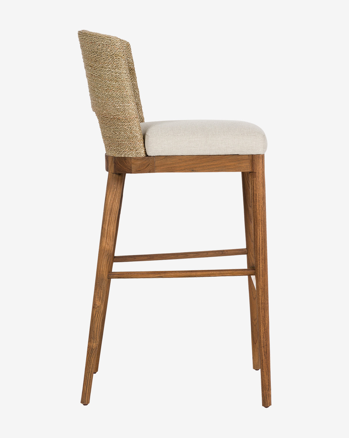Side view of the Ava Seagrass Counter Stool with a teak frame, light beige cushioned seat, and hand-woven seagrass backrest. Features four angled legs with footrests, shown against a plain white background.