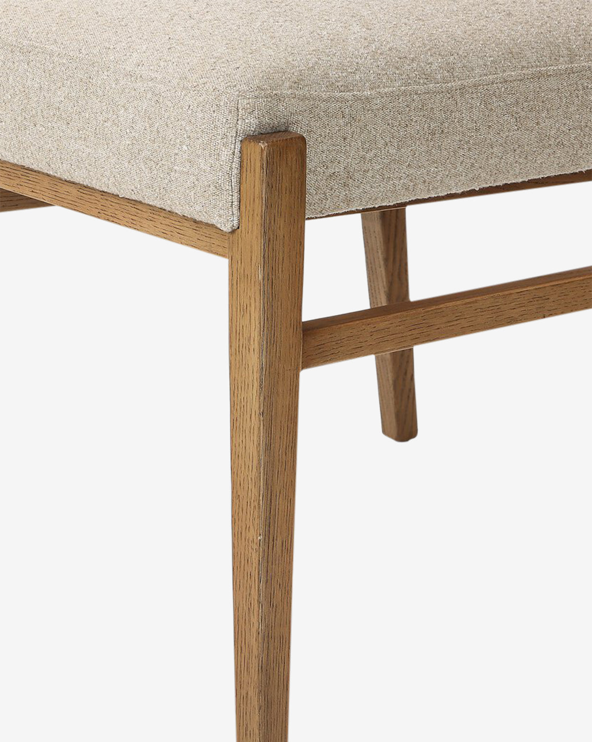 The Bailey Dining Chair features a cushioned beige upholstered seat, smoked oak wooden legs and frame with a natural finish, highlighting its modern minimalist design against a white background by McGee & Co.