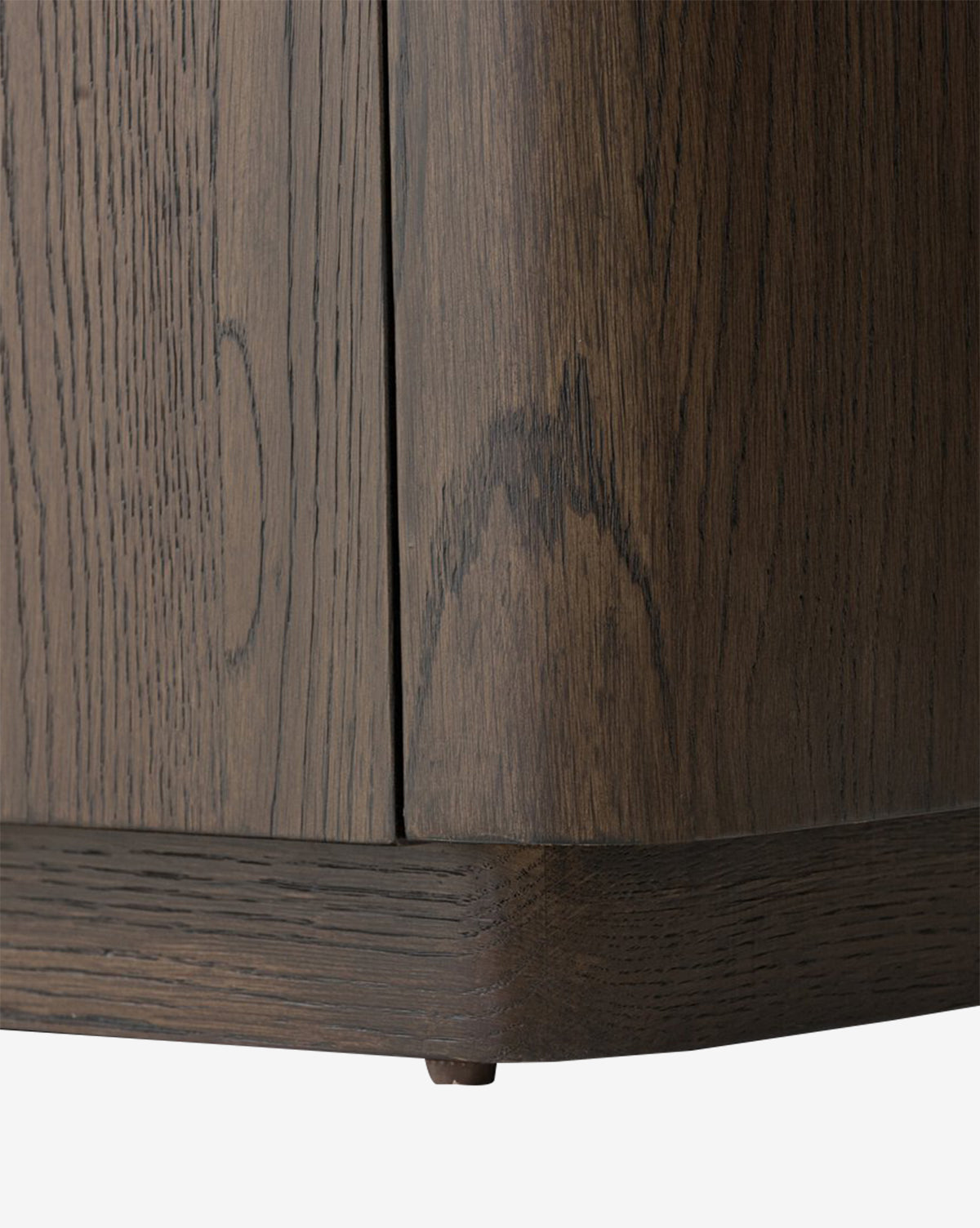 Close-up of the Baldwin Sideboards corner, featuring dark brown oak veneer with visible wood grain, smooth finish, and highlighting the bottom edge with a small round metal foot by McGee & Co.