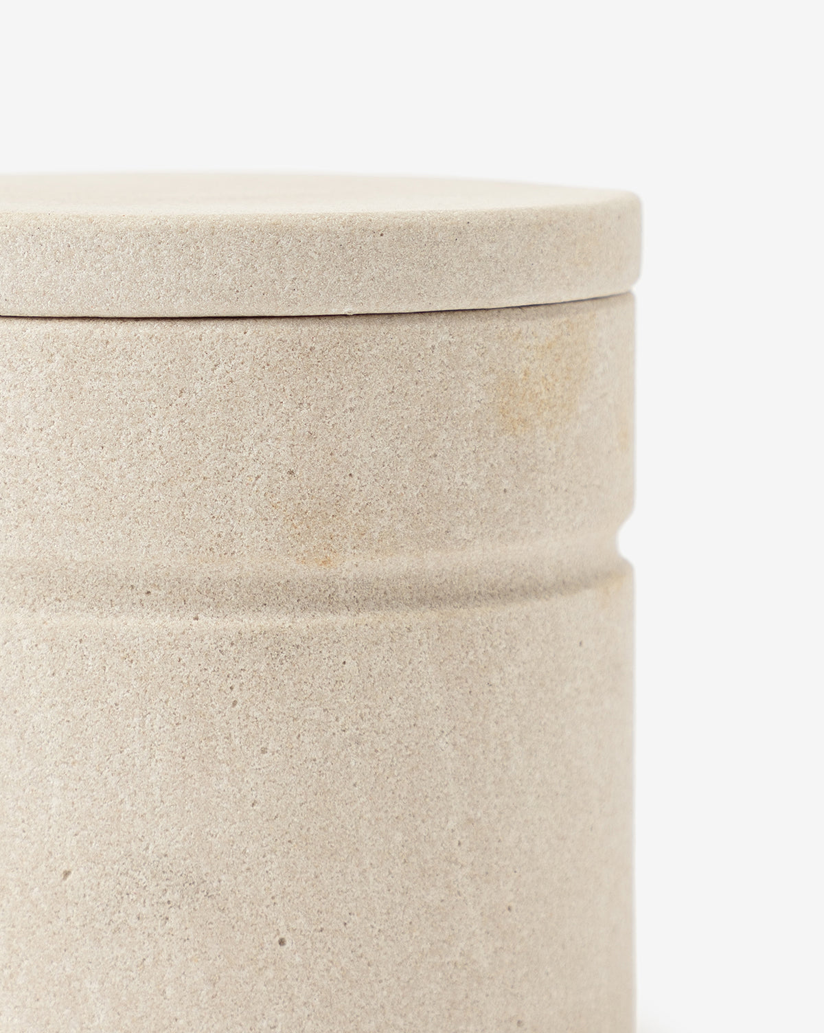A close-up of the Barton Sandstone Canister—round with a fitted lid, smooth beige texture, and simple design—makes it an ideal decorative piece for bathroom countertops set against a white background.