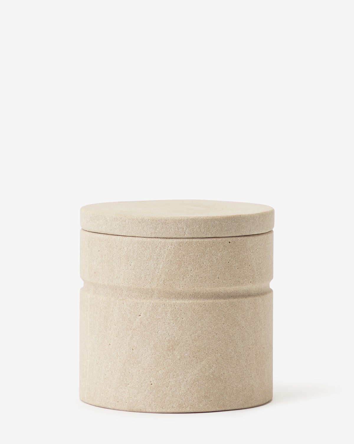 The Barton Sandstone Canister is a cylindrical, beige canister with a fitted lid and matte finish, designed as a decorative accessory ideal for bathroom countertops, displayed on a plain white background.
