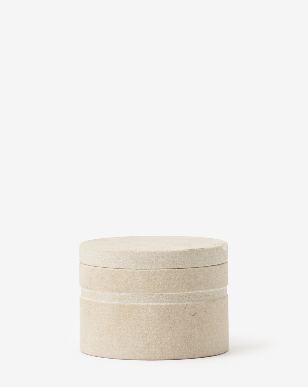 The Barton Sandstone Canister is a small, round container with a fitted lid, crafted from stone-like material, ideal for adding decorative style to bathroom countertops against a plain white background.