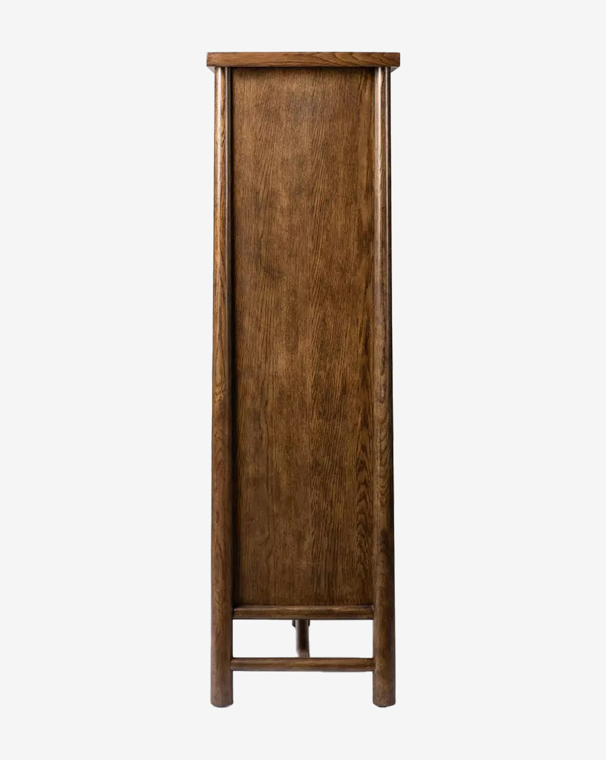 The Beasley 3-Door Cabinet is a tall, narrow piece with a flat top, simple design, and dark toasted oak finish. It stands on four straight legs with a horizontal support bar near the bottom and is viewed from the side by McGee & Co.