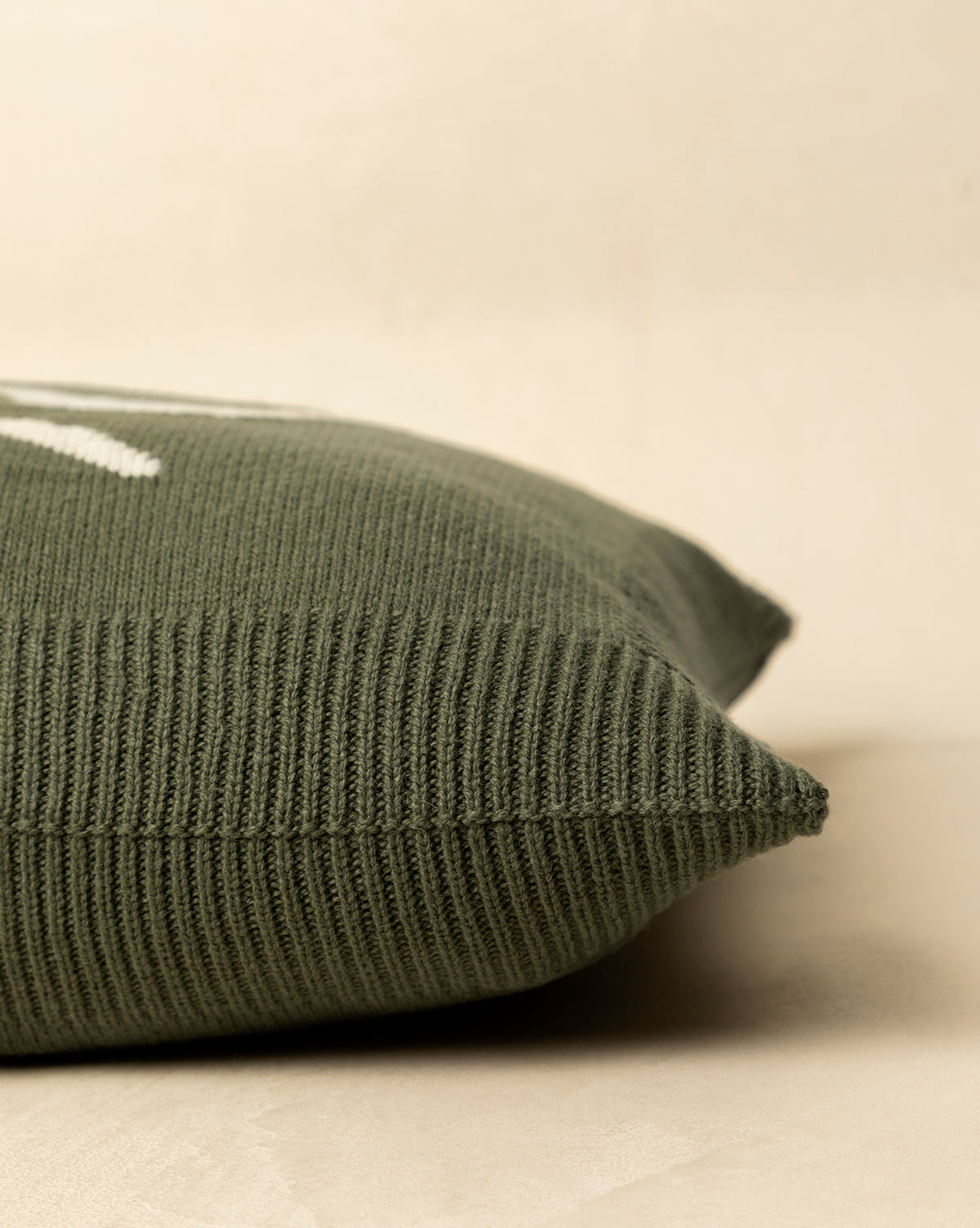 Close-up of the green Bella Pillow Cover, featuring a knit texture and white stitching, displayed on a light surface against a neutral background—ideal for holiday layering, by McGee & Co.