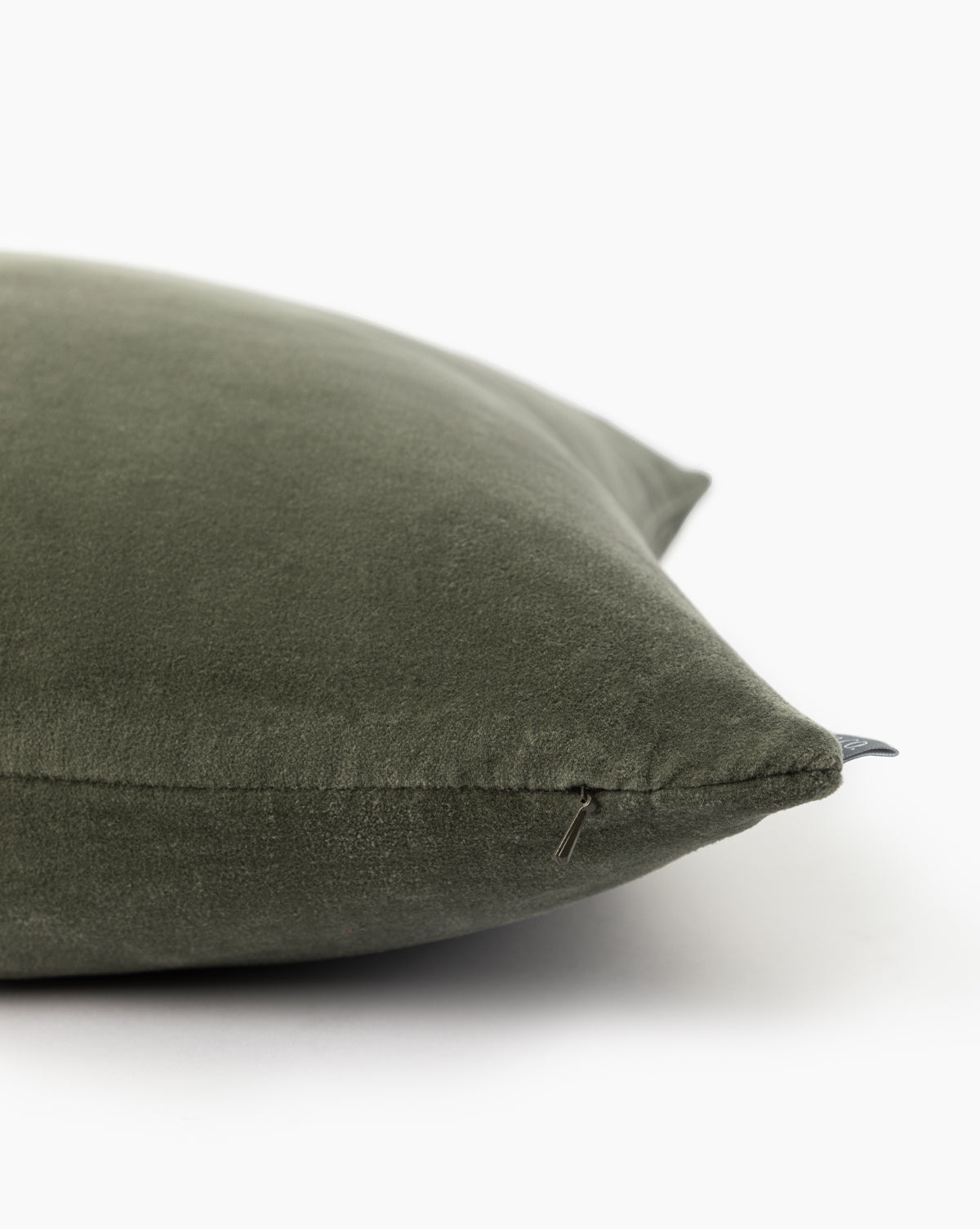 A close-up of the Bellevue Velvet Pillow Cover in green stone washed velvet, featuring a visible zipper on one edge, set against a white background, by McGee & Co.