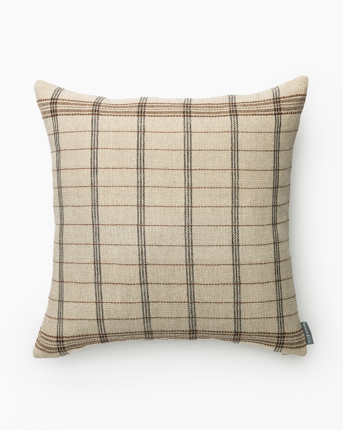 The Benedict Pillow Cover features a beige base with brown and dark gray plaid, seen from above on a white background. A small fabric tag is visible at the bottom right, adding stylish accent to any home décor, by McGee & Co.
