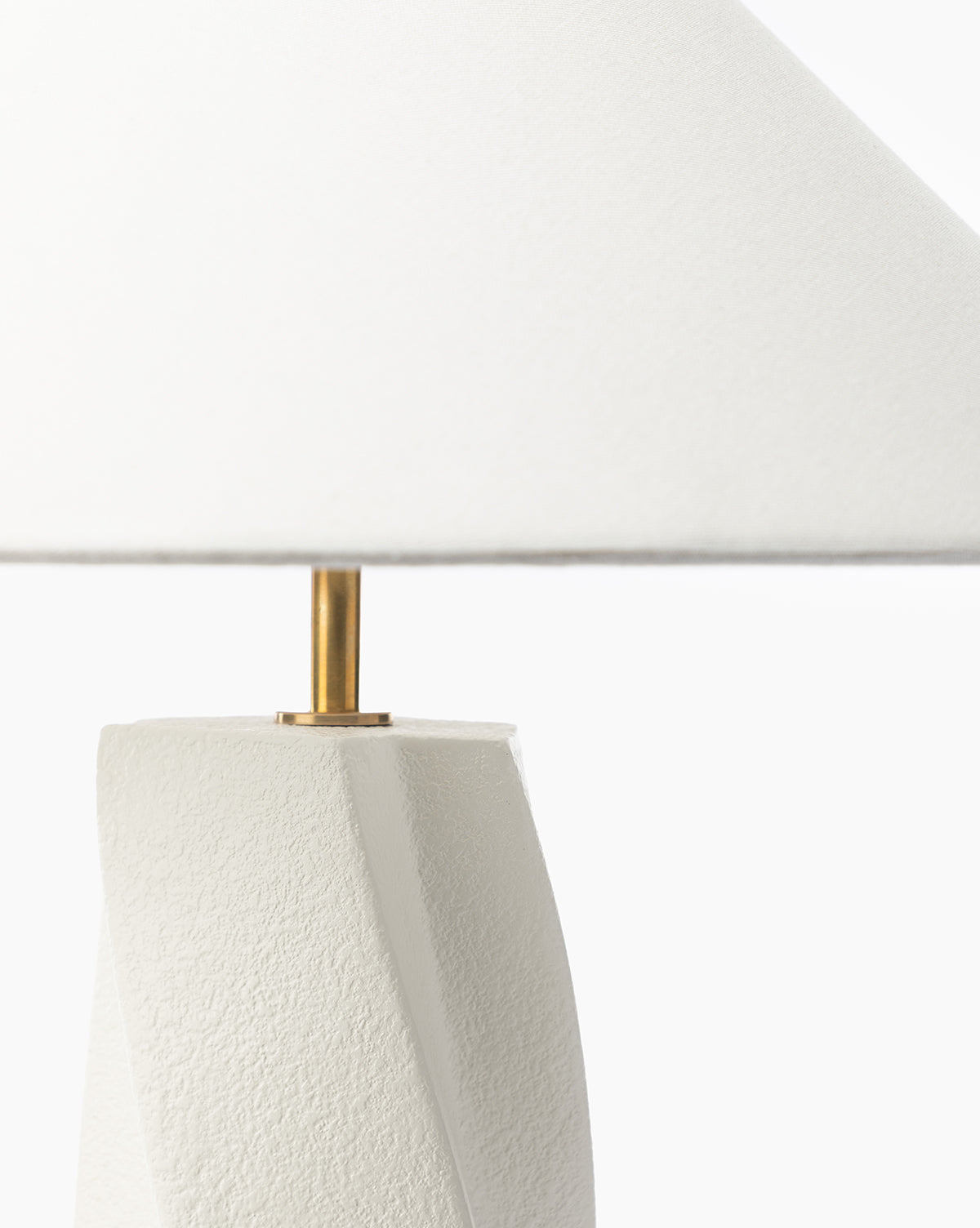 A close-up of the Bettencourt Table Lamp shows its textured white resin base, gold stem, and large linen shade set against a plain white background, by McGee & Co.