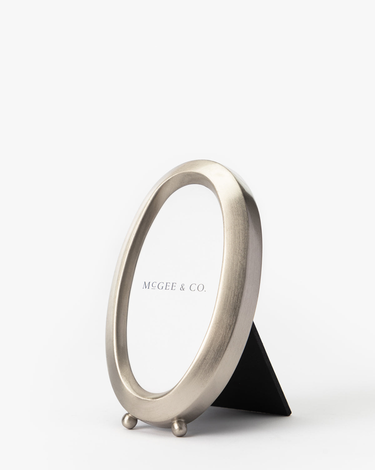 The Blanche Pewter Picture Frame features iron corners and a simple stand, displayed at an angle with a placeholder paper labeled MCGEE & CO. on a plain white background for a sophisticated look.