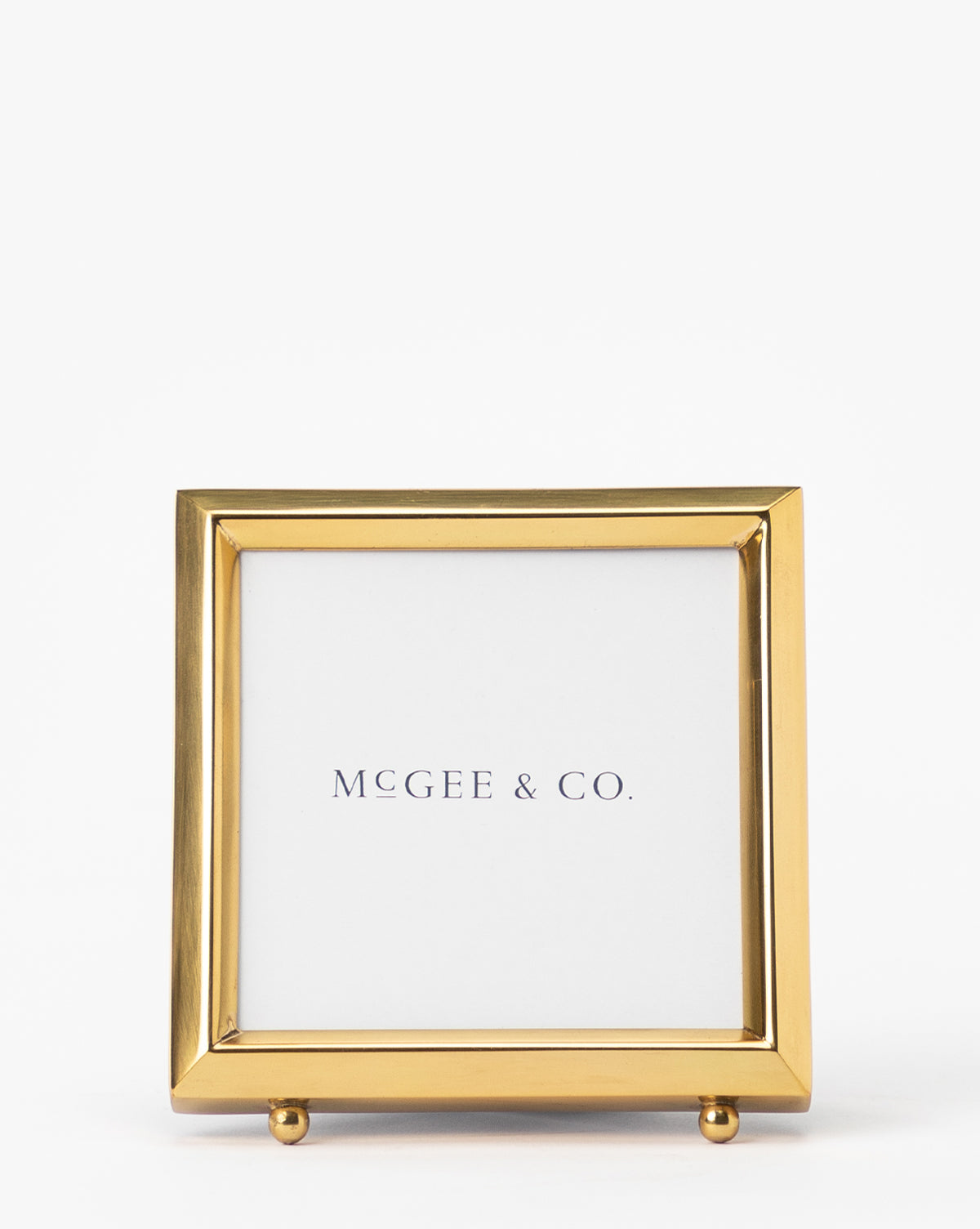 The Blanche Picture Frame features a square gold metal frame with a white mat, displaying the text McGEE & CO. centered on a plain white background.