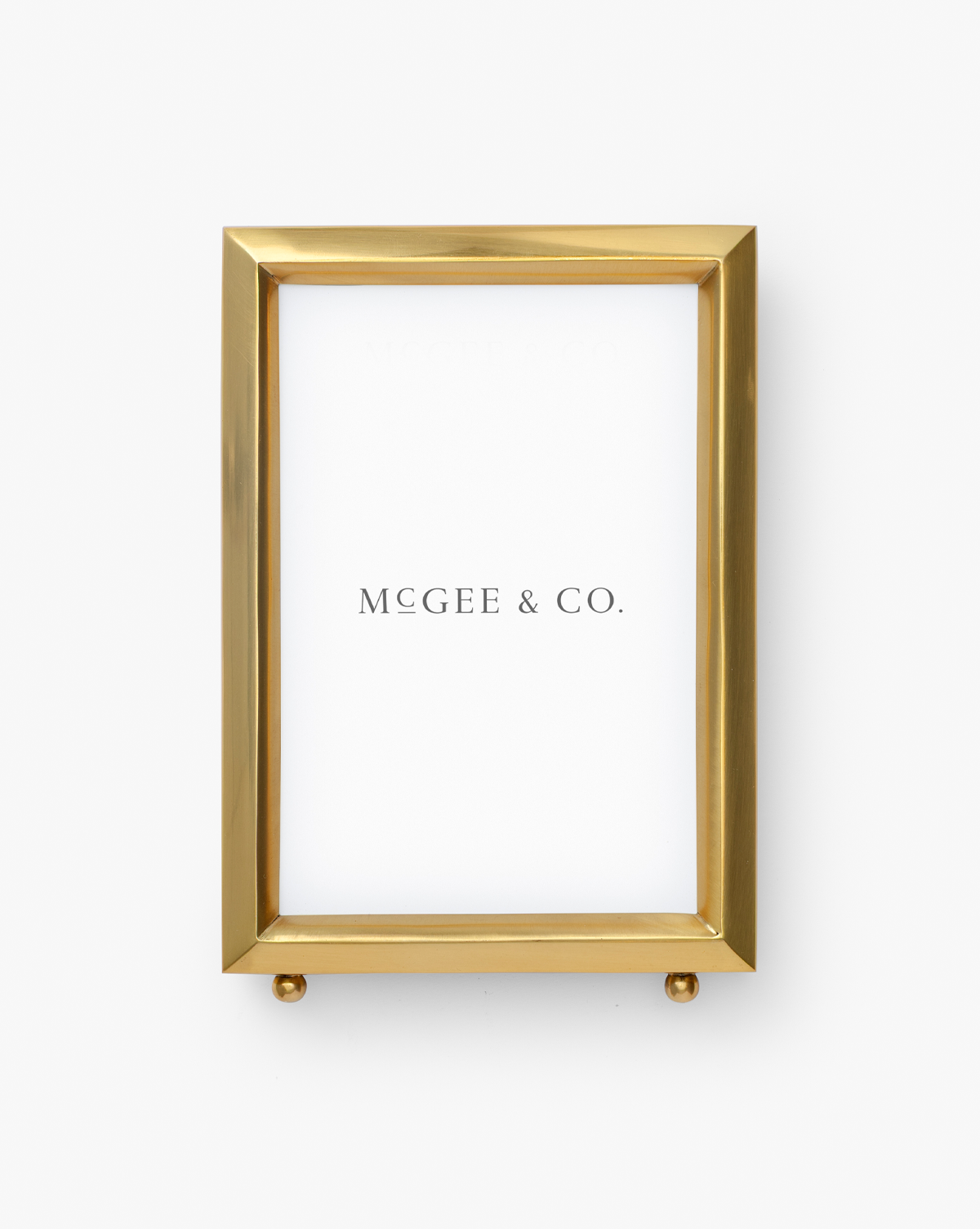 A gold Blanche Picture Frame featuring a polished brass finish and white background, with “McGee & Co.” elegantly in black lettering, by McGee & Co.