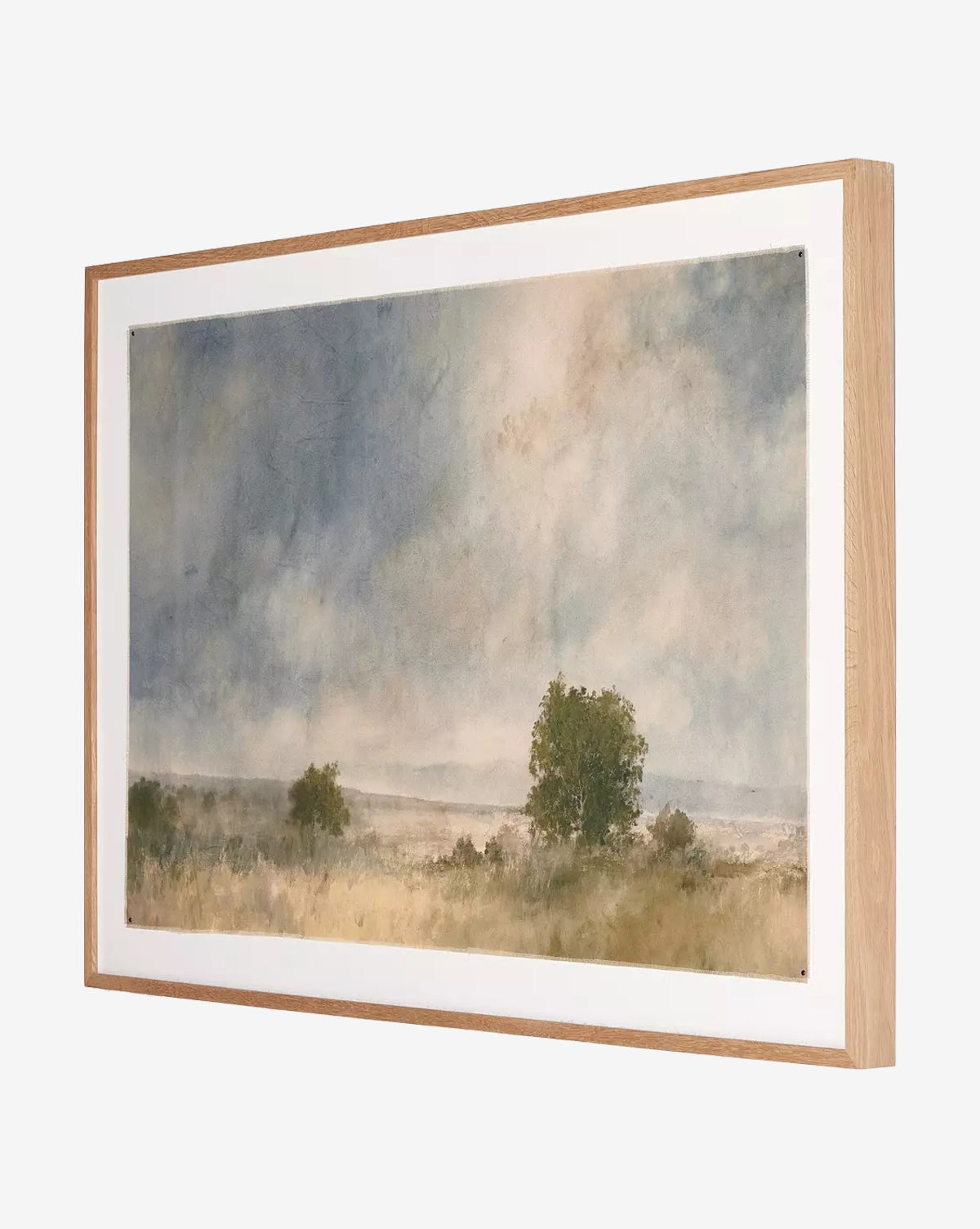 Blue Spendor by Aileen Fitzgerald is a framed watercolor landscape with muted tones, depicting a cloudy sky over fields and distant hills. Its light-colored white oak frame enhances the artwork’s soft, impressionistic style.