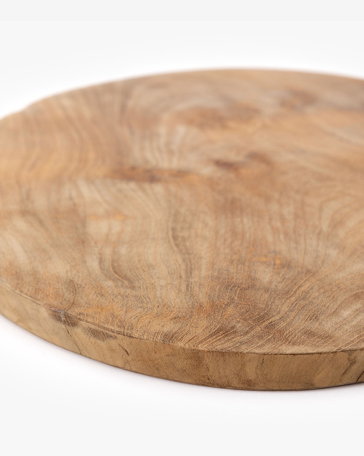 The Boylan Bread Board is a round, flat teak wood board featuring visible natural wood grain and shown resting on a white surface.