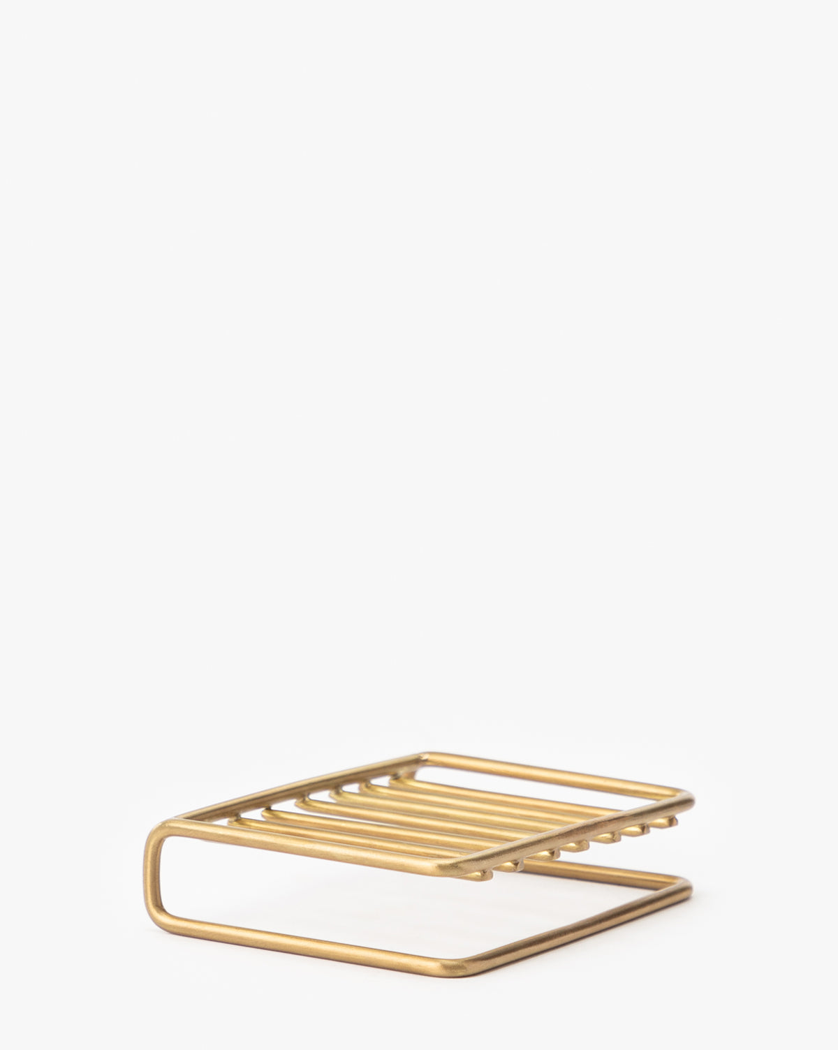 The Brass Soap Dish features a minimalist rectangular design with parallel bars and an open, elevated structure, ideal for bathroom countertops. Shown on a plain white background.