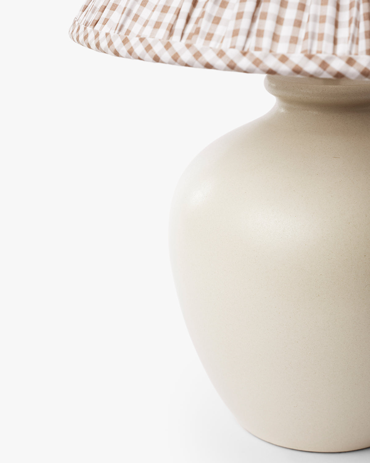 Close-up of the Bronwyn Table Lamp featuring a beige ceramic base and a brown-and-white gingham pleated shade, set against a plain white background, by McGee & Co.