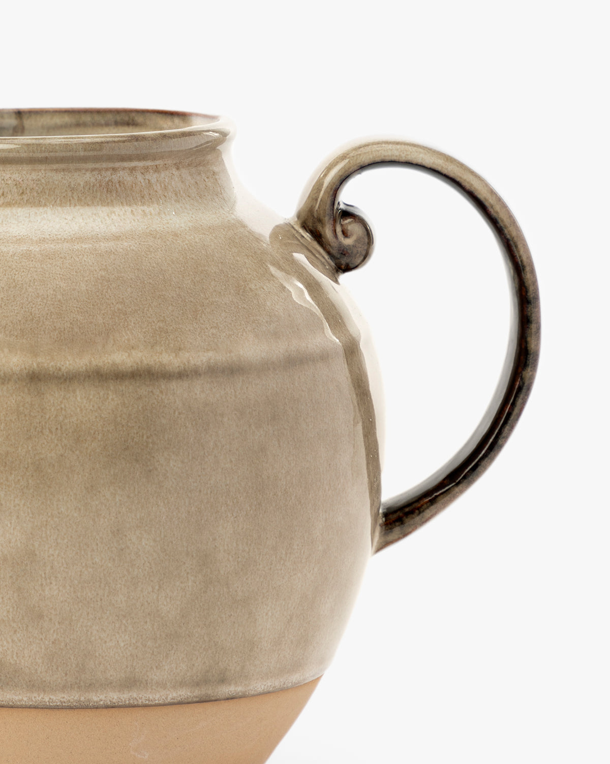 Close-up of a beige ceramic mug with a rounded body and looped handle, set against a white background—perfect for kitchen styling when paired with your Brown Stoneware Pitcher, by McGee & Co. Only half of the mug is visible in the image.