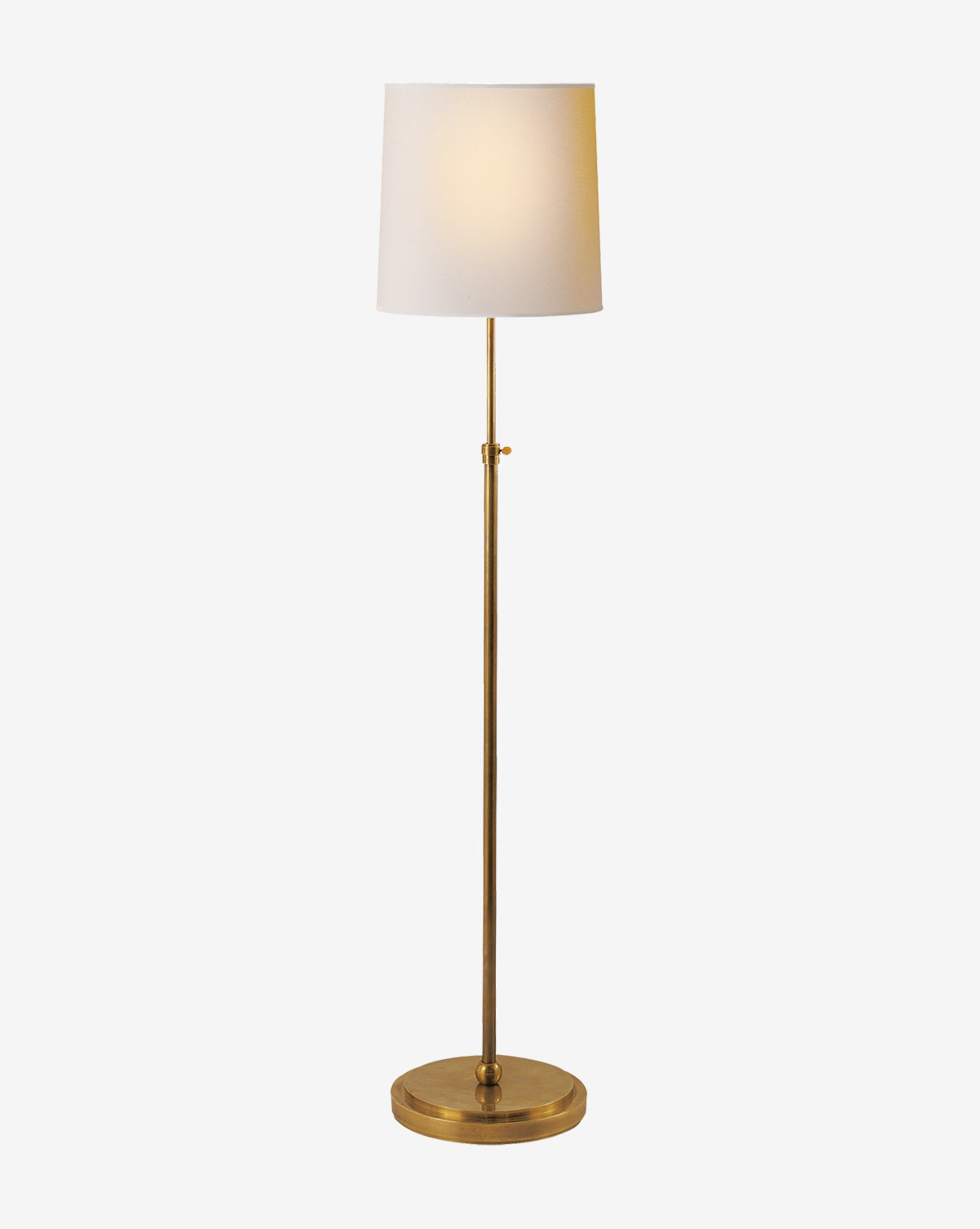 The Bryant Floor Lamp boasts a brass stand and round base with a white linen shade, providing a warm glow. Its simple elegance makes it ideal for contemporary interiors, by McGee & Co.