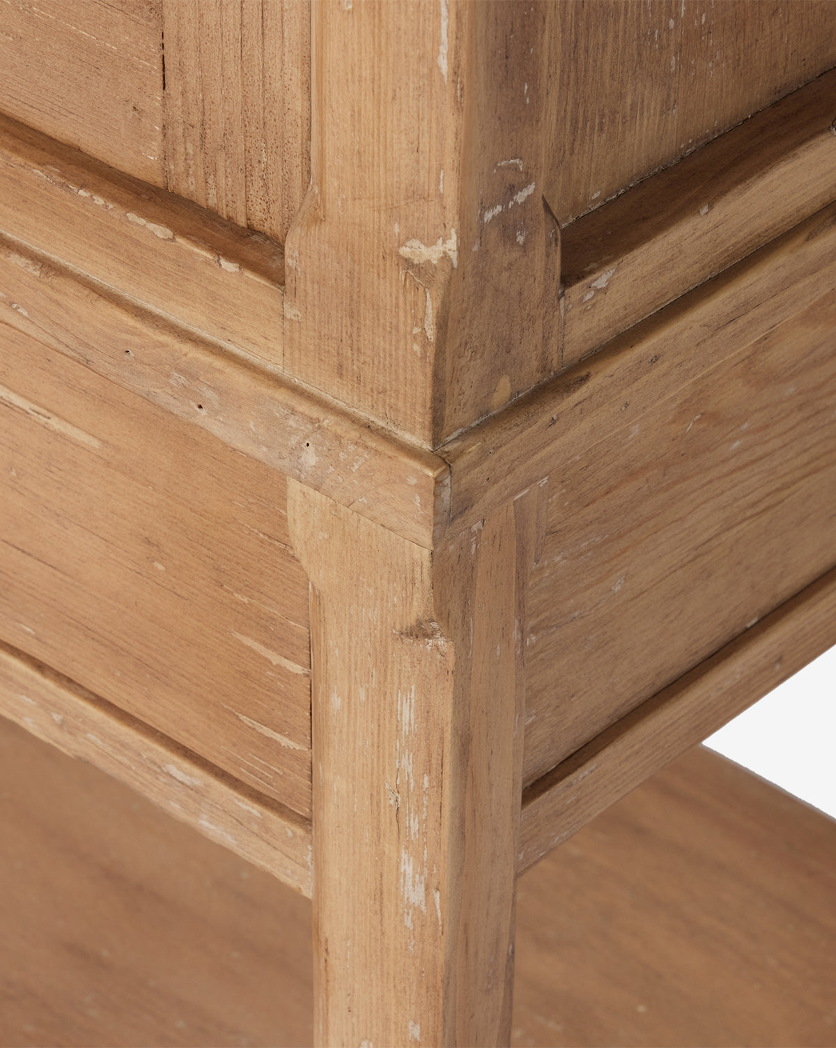 Close-up of the Bryn Cabinet’s corner, crafted from solid pine, highlighting its natural wood grain, detailed joinery, and areas with slight wear and chipped paint for a rustic, weathered look, by McGee & Co.