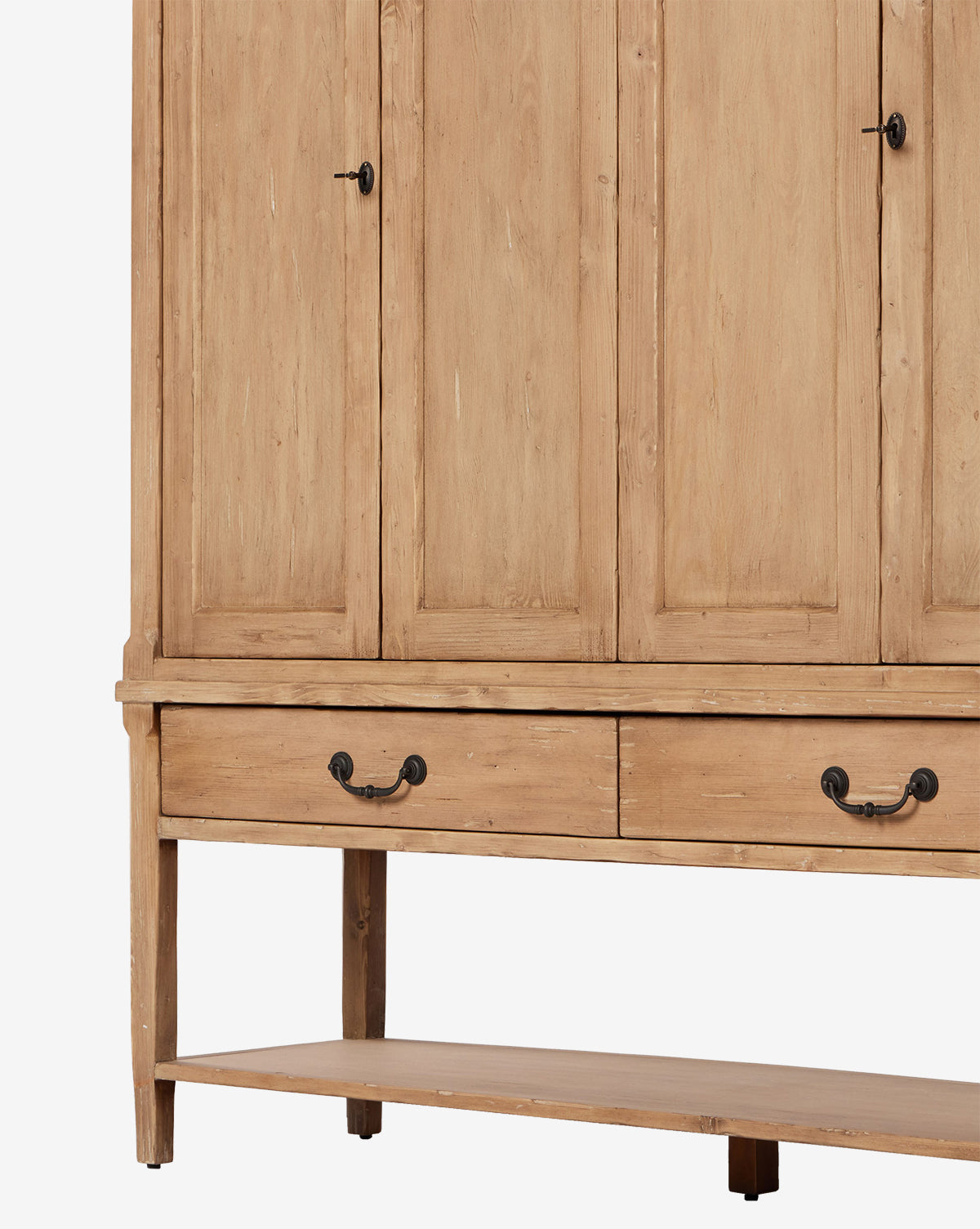 The Bryn Cabinet is crafted from solid pine with a natural light finish, featuring distressed copper hardware, two spacious drawers, a lower open shelf, and four tall paneled doors for extra storage, by McGee & Co.