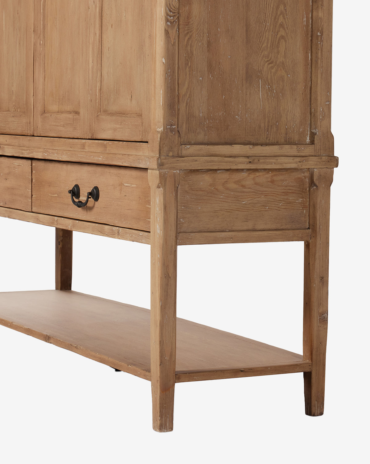 A close-up of the Bryn Cabinet, made from solid pine with a natural rustic finish, visible grain and texture. It features a drawer with distressed copper hardware, straight legs, and a lower shelf by McGee & Co.