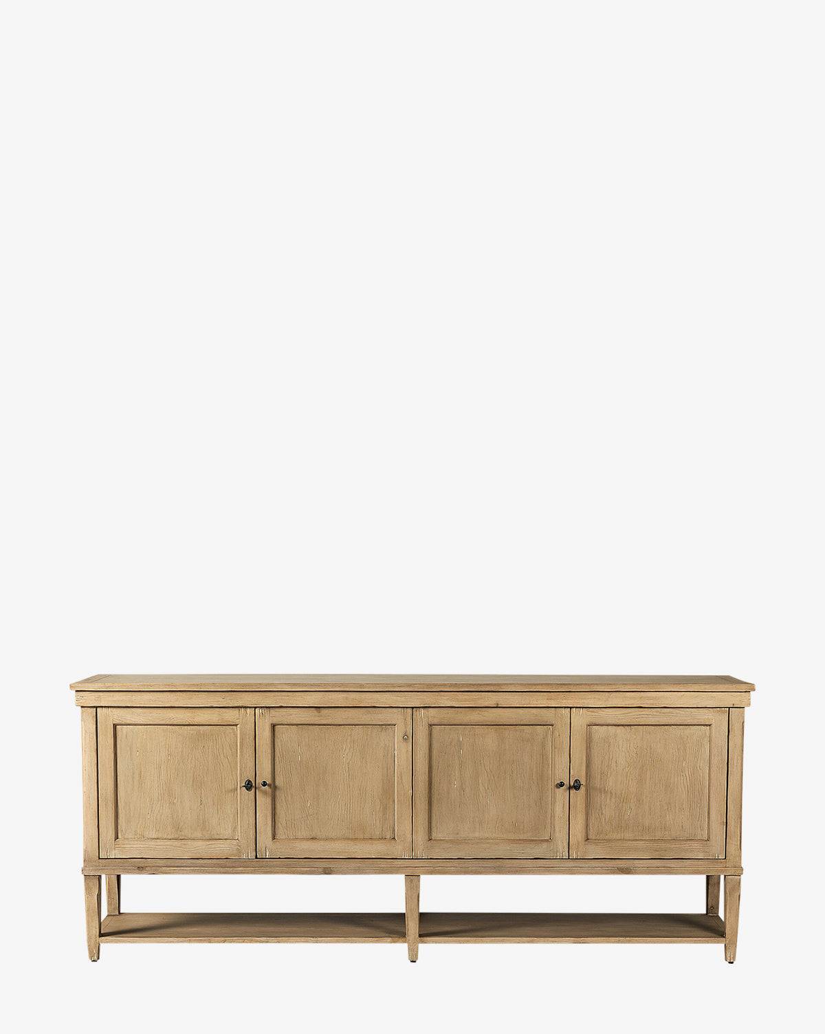 The Bryn Sideboard is crafted from solid pine with four paneled doors, round knobs, distressed copper hardware, a natural finish, and an open lower shelf, by McGee & Co.