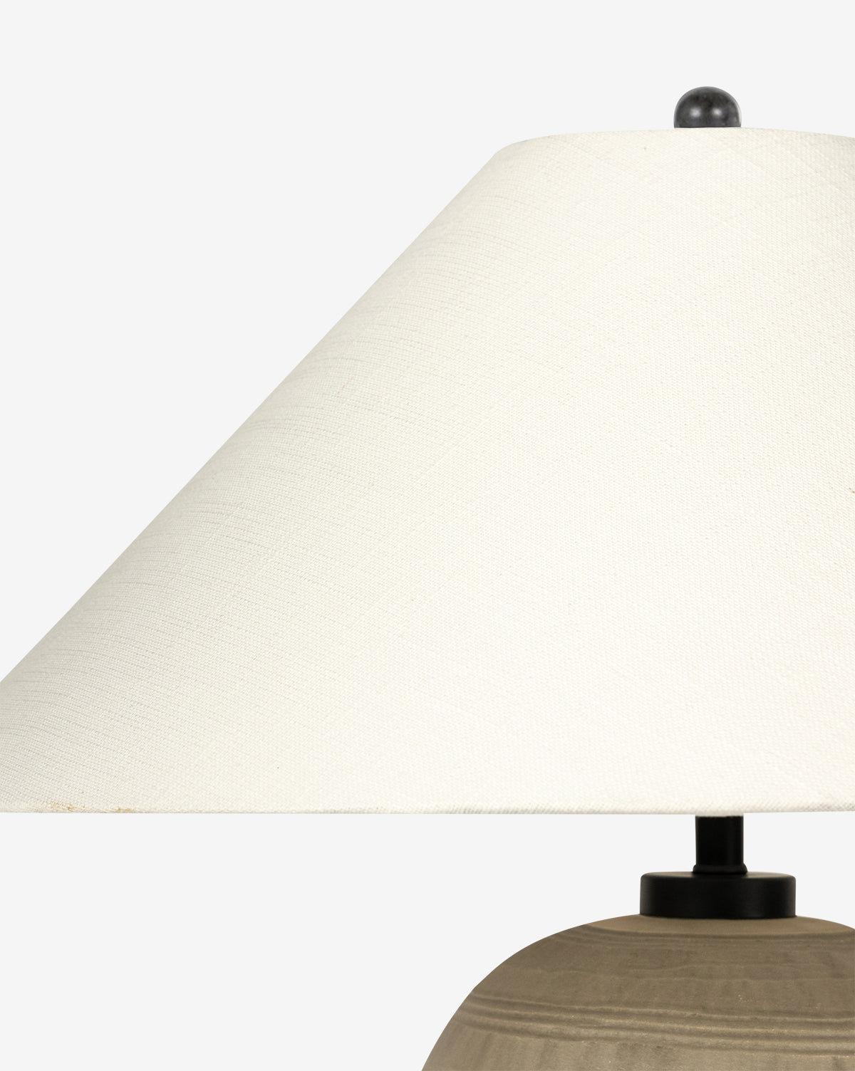 The Brynner Table Lamp features a textured off-white shade and a smooth, round neutral base, ideal for transitional decor, by McGee & Co. Shown in close-up against a plain light background.