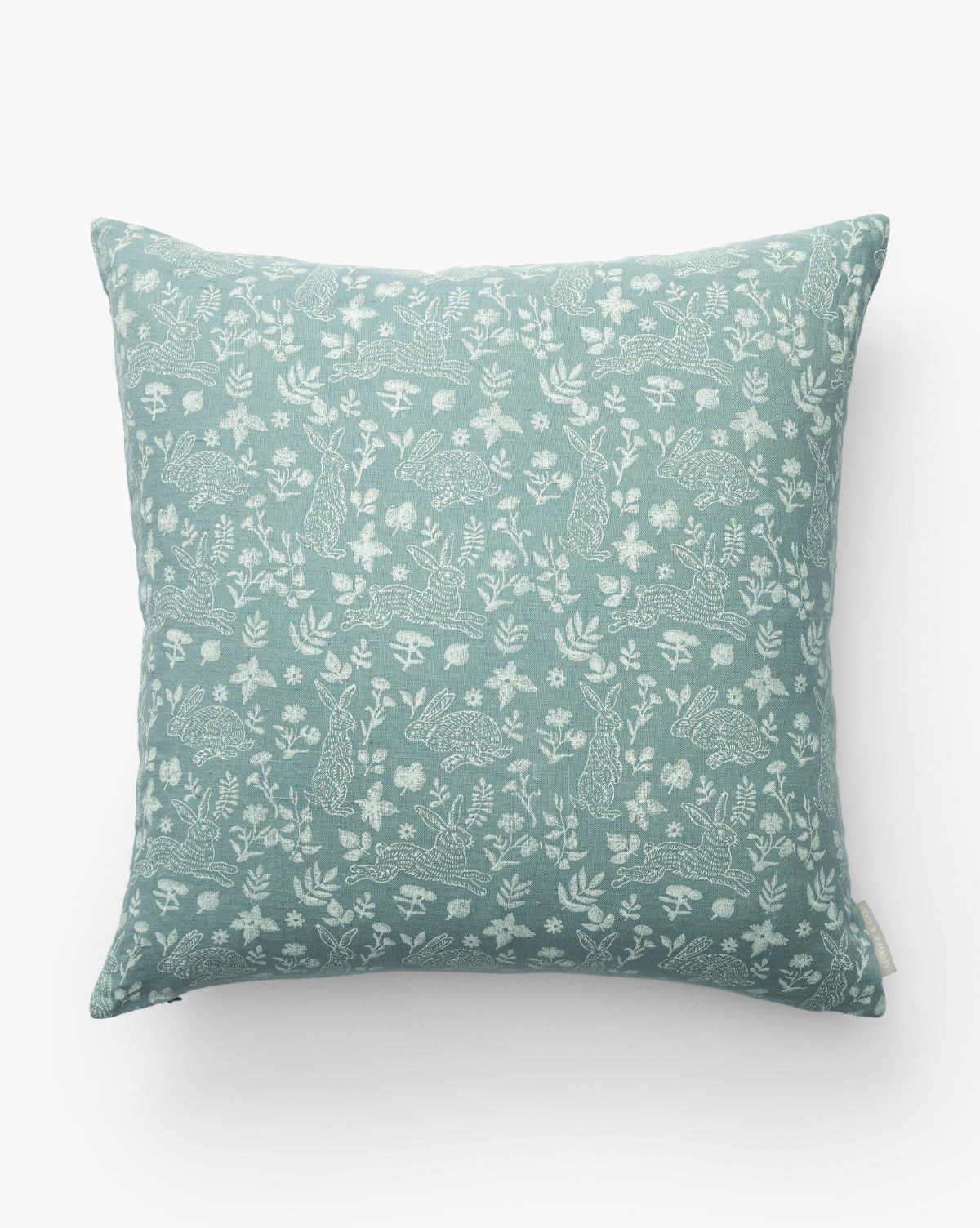 The Bunny Blockprint Pillow Cover features a square, light blue-green design with white rabbits, hedgehogs, mushrooms, and plants in a nature-inspired block print on white linen, by McGee & Co.