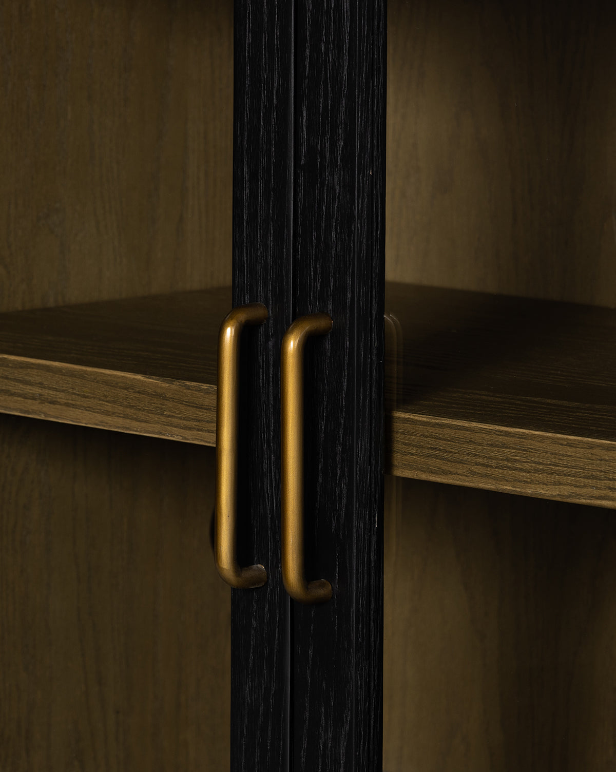 Close-up of two gold handles on dark wooden doors of the Burton Sideboard, featuring a middle shelf and light wood interior in the background, by McGee & Co.