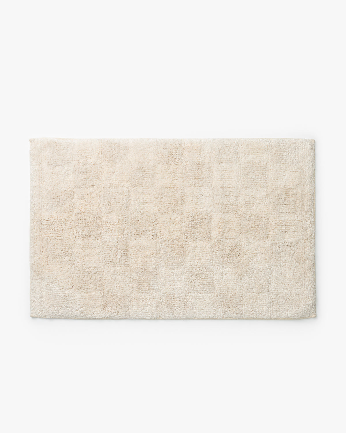 The Callen Bath Mat, a rectangular cream-colored cotton mat with a subtle checkered pattern, is displayed on a white background.