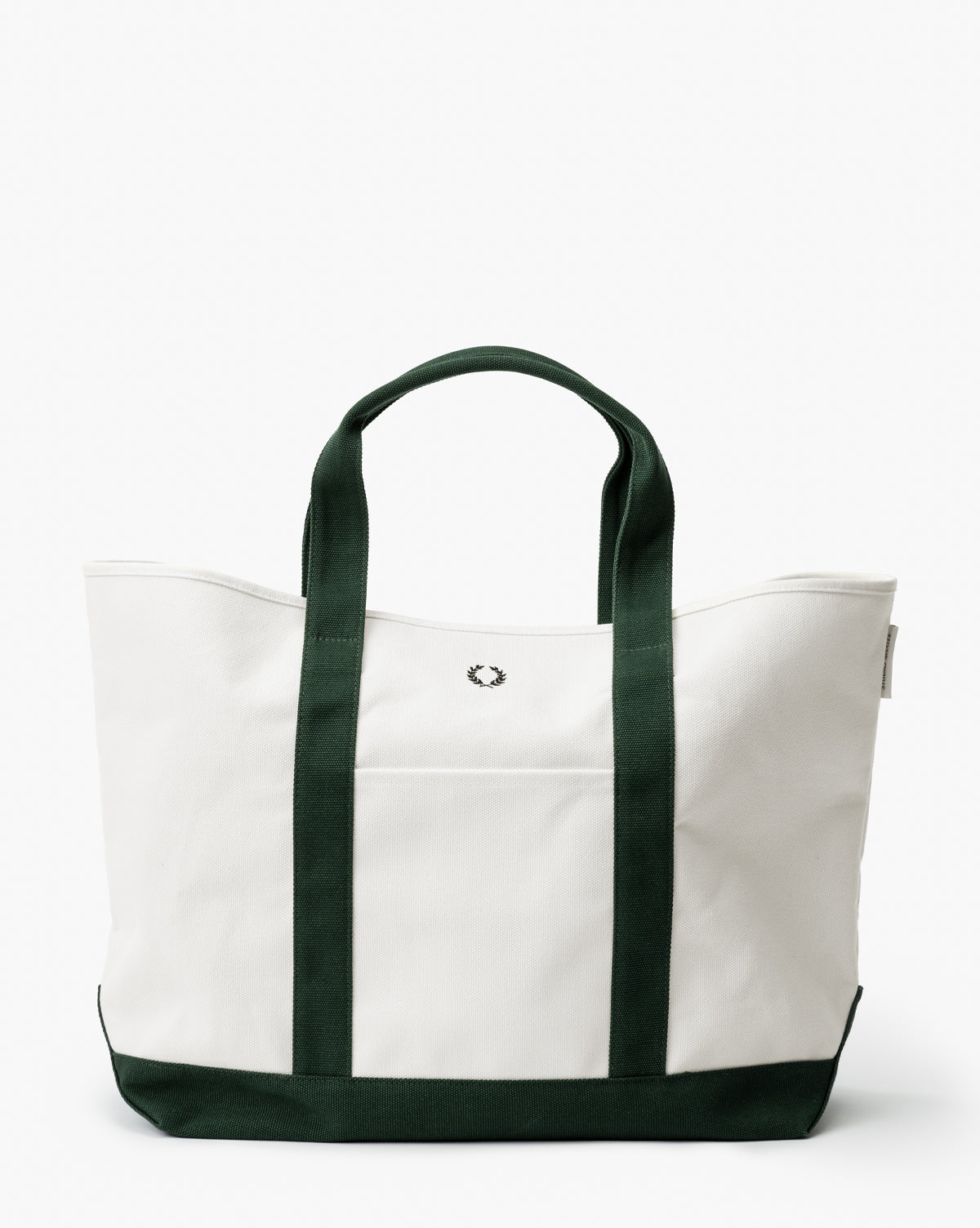 The Canvas Laurel Tote is a spacious white tote with dark green handles, trim, and bottom. It has a small embroidered logo on the front and an exterior pocket for convenience, by McGee & Co.