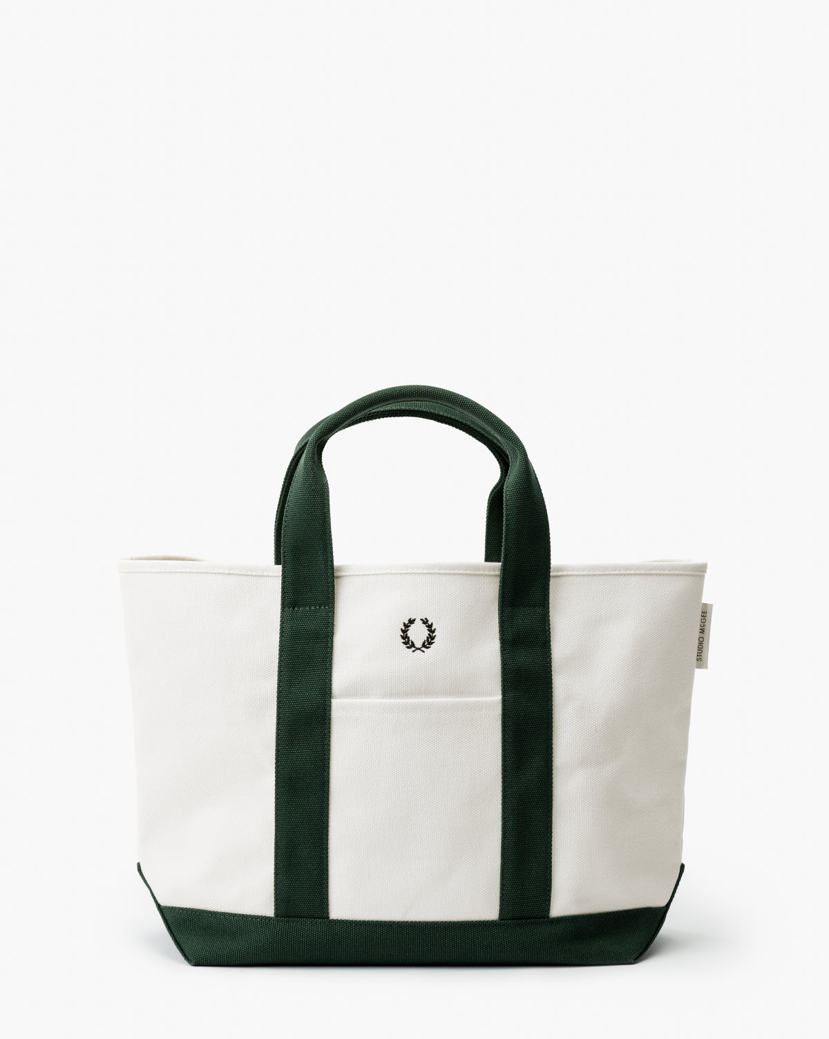 The Canvas Laurel Tote features a white canvas body with dark green handles and trim, plus a small black laurel wreath logo on the front—ideal for everyday use or fans of timeless Studio McGee style, by McGee & Co.