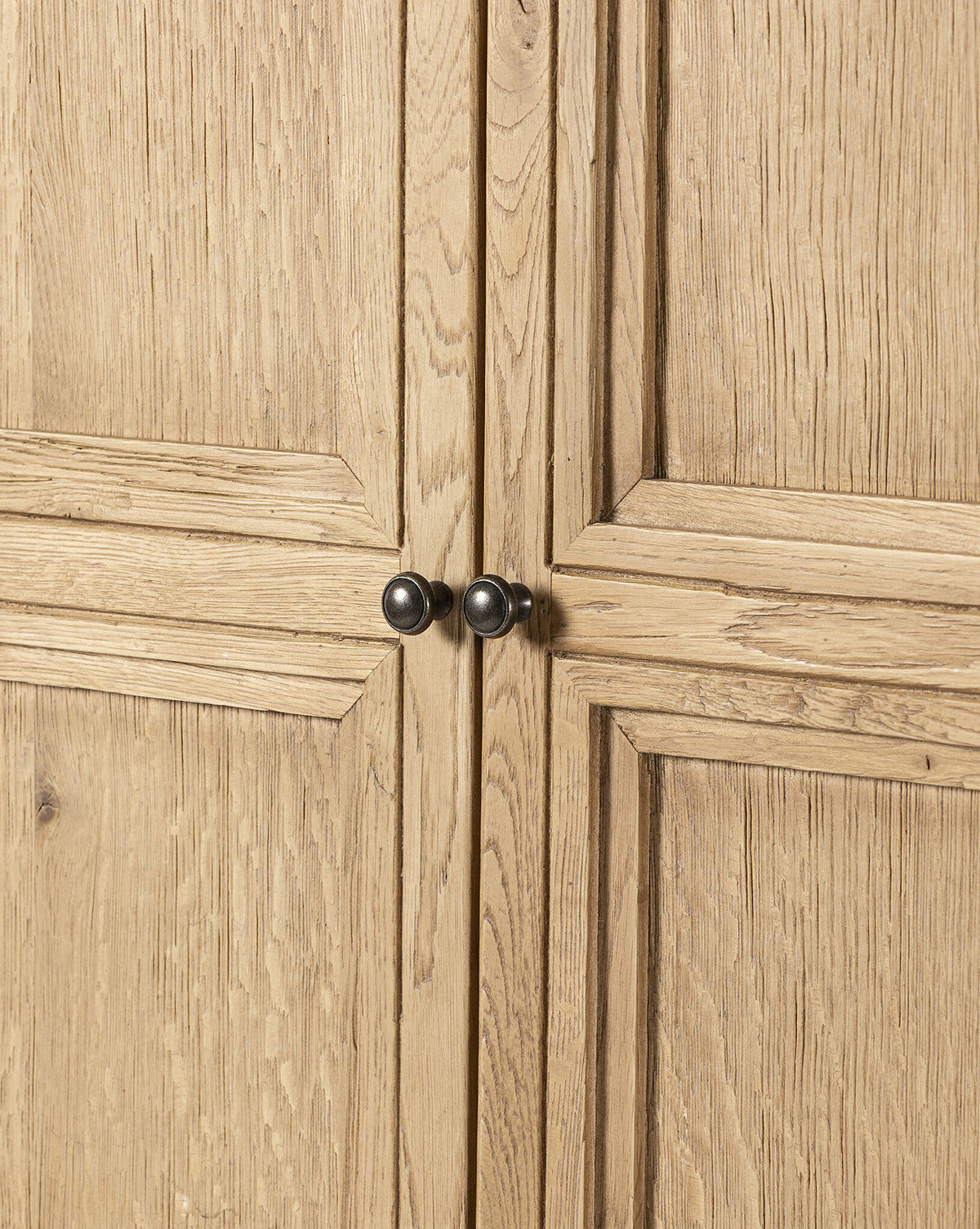 Close-up of Carrington Cabinet doors in worn oak with a light, natural grain and two central round, bronze-finished knobs, by McGee & Co.