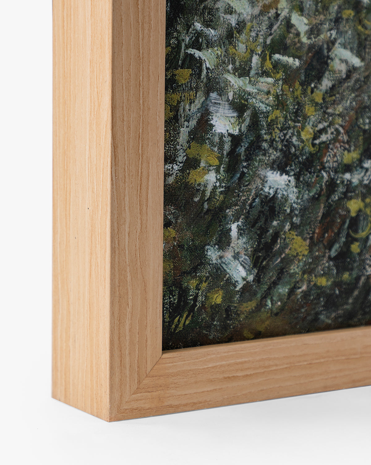 Close-up of the bottom left corner of a natural oak wood frame, highlighting the edge of Carved Path, a giclee on canvas with green, white, and yellow textured brushstrokes, by McGee & Co.