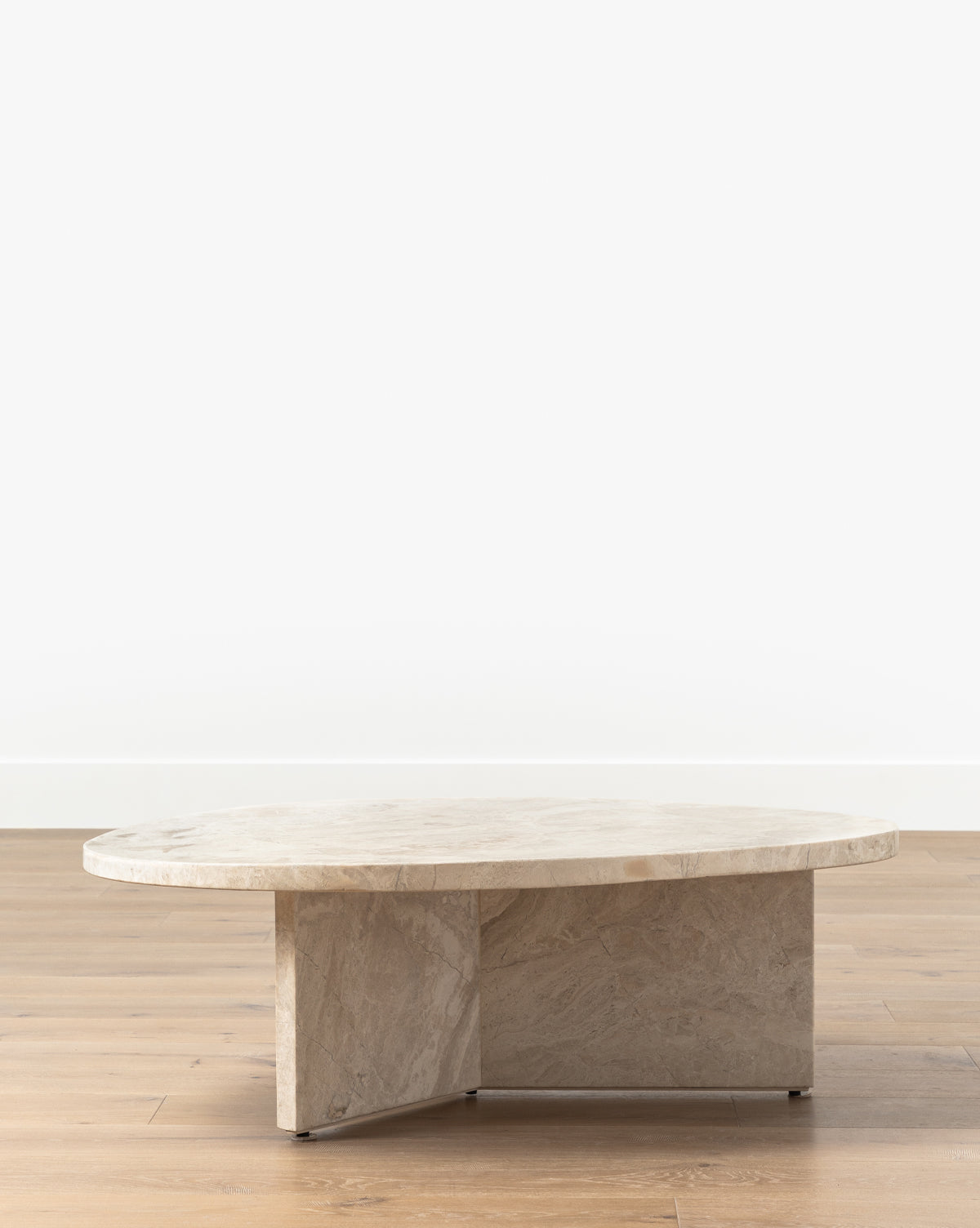 The Cassius Coffee Table boasts a round, thick Turkish Dyna Marble top and a solid intersecting base, creating a modern look ideal for placement on light wooden floors against white walls, by McGee & Co.