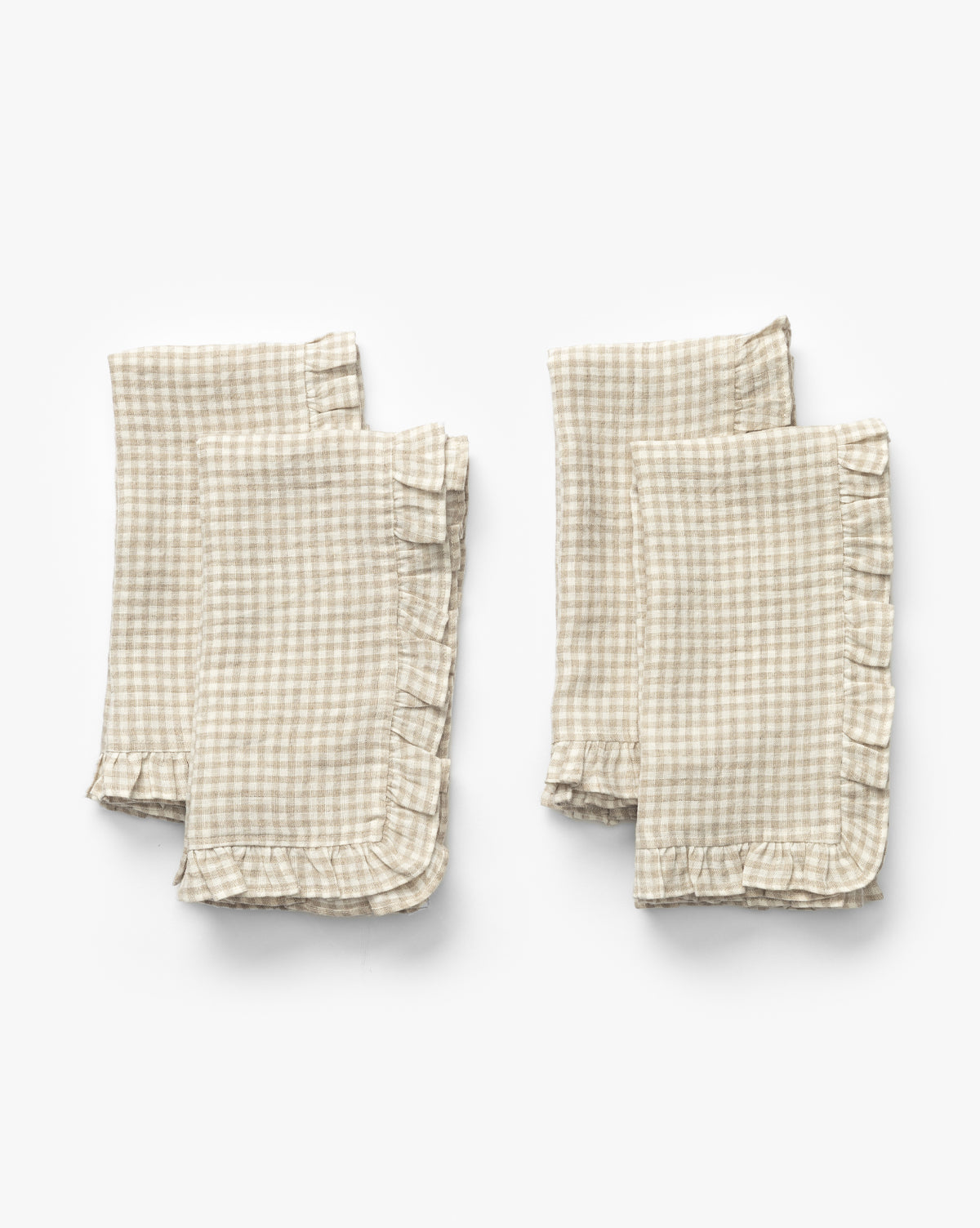 The Catania Linen Napkins (Set of 4) feature a small checkered pattern and ruffled edges, shown folded in two pairs on a white background, by McGee & Co.