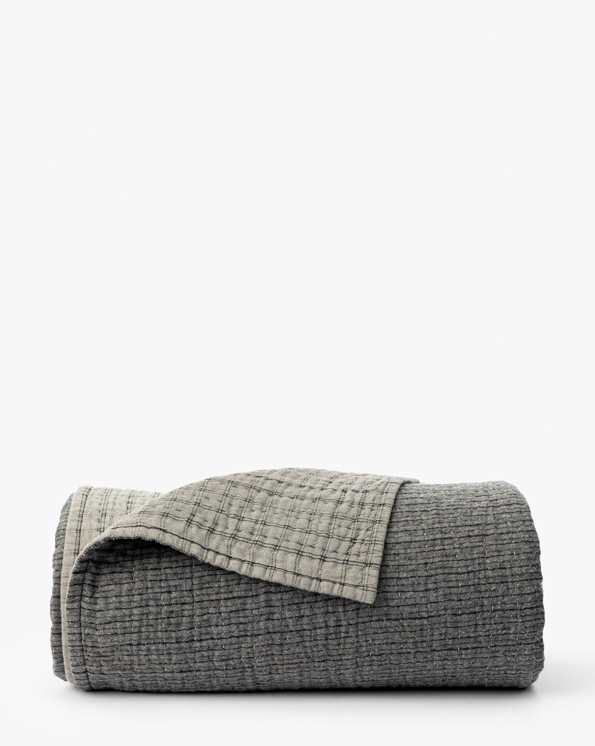 The Cecily Kids Quilt by Renuka Inc. features a neatly folded, textured gray design with a lighter gray grid-patterned underside, displayed on a white background. McGee & Co.