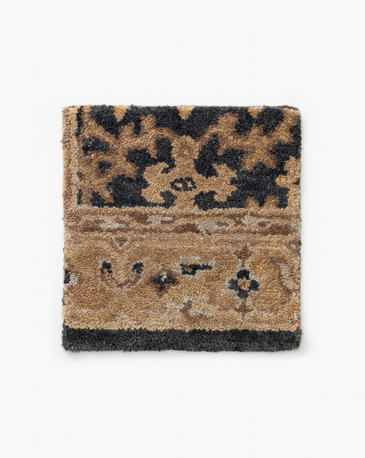 The Chandler Rug Hand-Tufted Swatch features a square sample of patterned carpet with black, beige, and brown floral designs inspired by traditional textiles. Each side has distinct motifs on a plain white background, by McGee & Co.